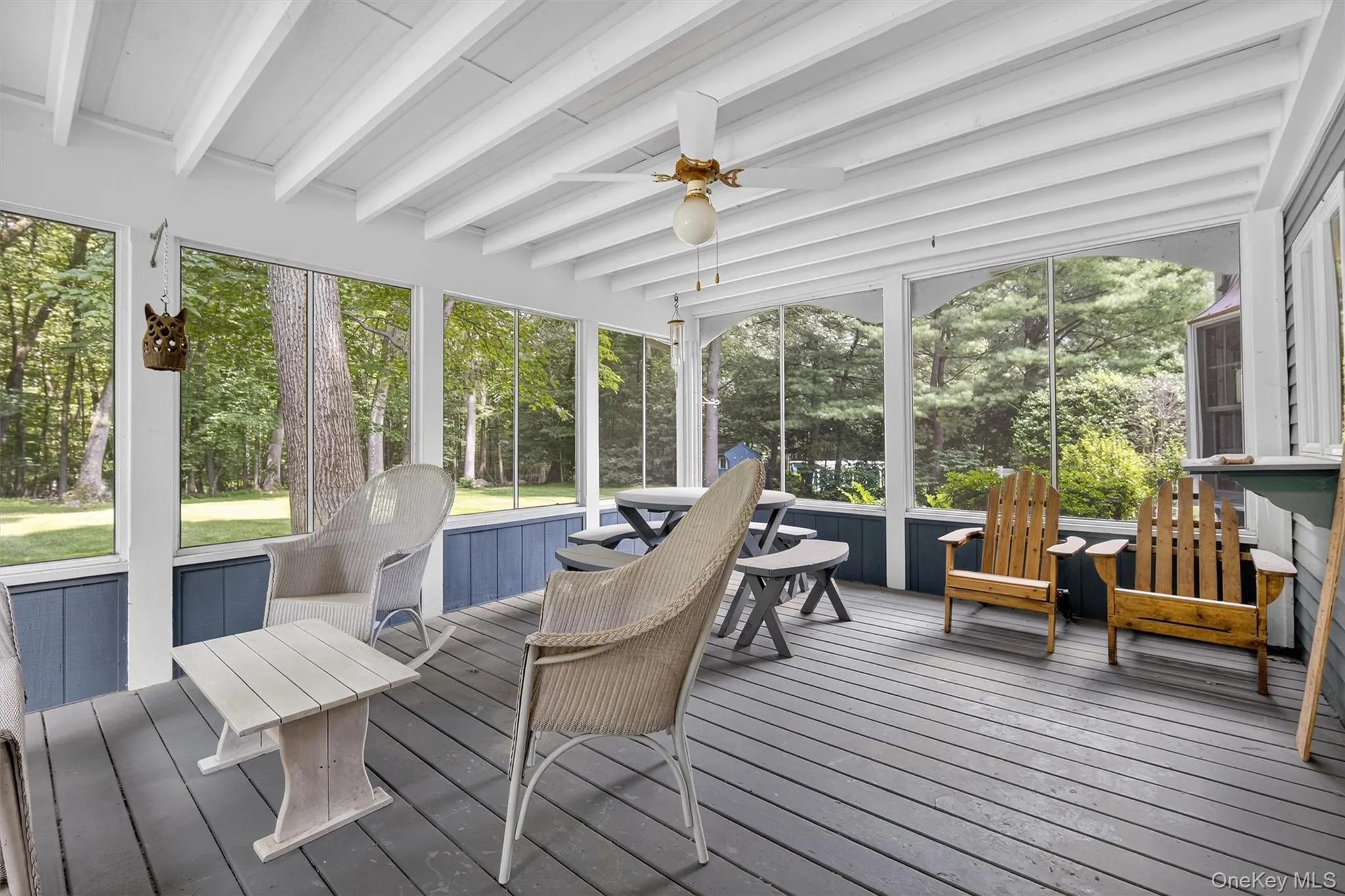 Sunroom / solarium featuring beam ceiling, a ceiling fan, and view of scattered trees Sunroom / solarium featuring beam ceiling, a ceiling fan, and view of scattered trees