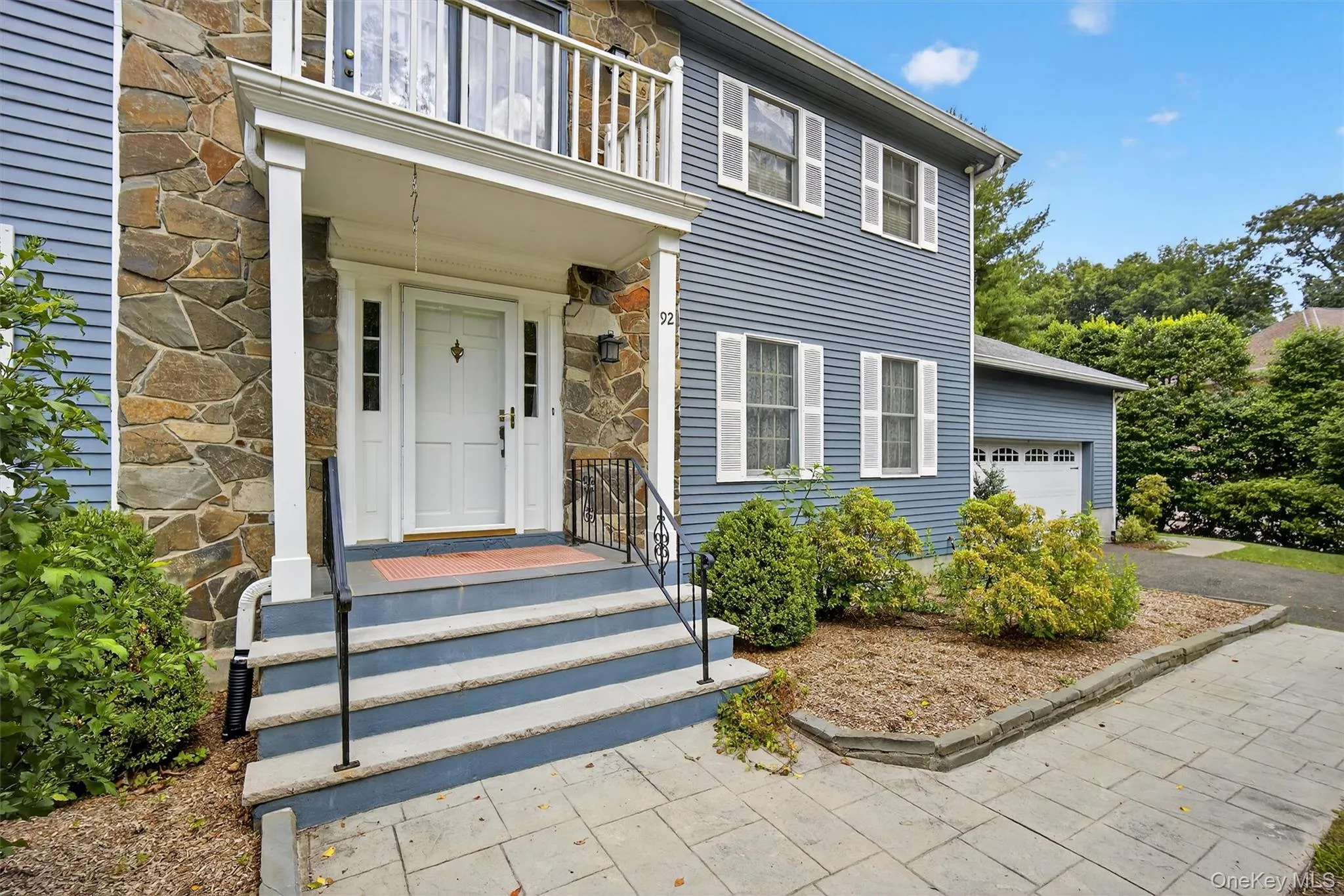 Doorway to property with stone siding, a balcony, and an attached garage Doorway to property with stone siding, a balcony, and an attached garage