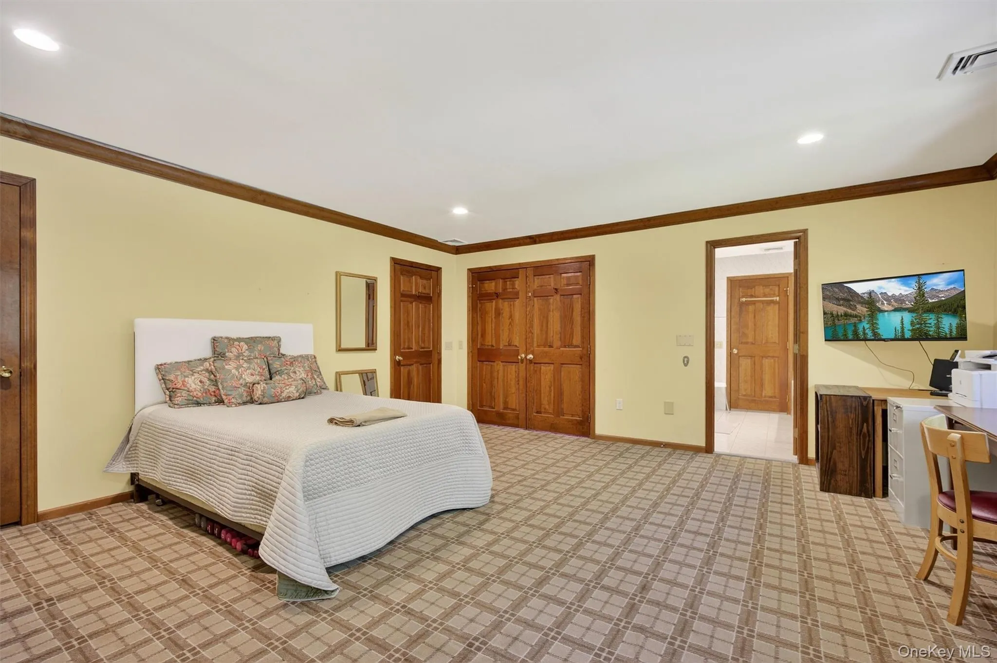 Bedroom featuring ornamental molding, recessed lighting, light colored carpet, a closet, and ensuite bath Bedroom featuring ornamental molding, recessed lighting, light colored carpet, a closet, and ensuite bath