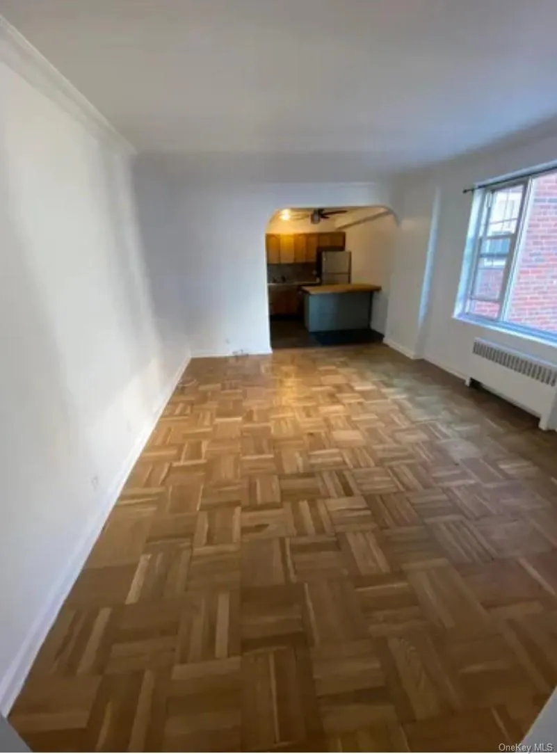 Unfurnished living room with radiator heating unit, arched walkways, and baseboards Unfurnished living room with radiator heating unit, arched walkways, and baseboards