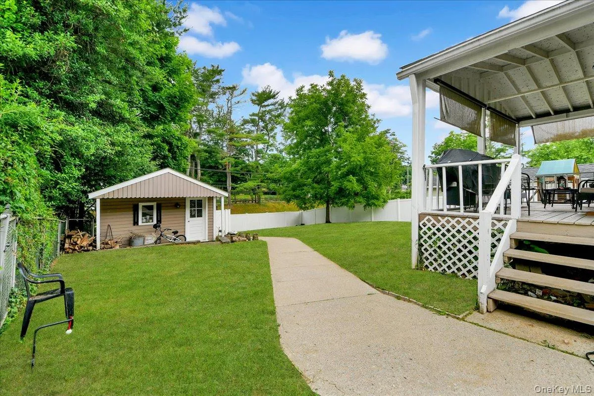 Expansive backyard featuring a covered patio, a detached storage shed, a concrete pathway, a chain-link fence, and a white privacy fence Expansive backyard featuring a covered patio, a detached storage shed, a concrete pathway, a chain-link fence, and a white privacy fence