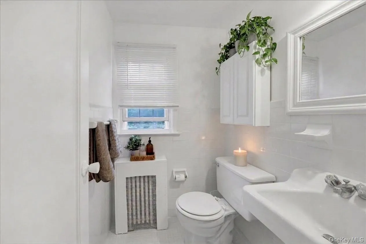 2nd floor half bathroom featuring white tile flooring, white subway tile wall surround, and a compact window with blinds 2nd floor half bathroom featuring white tile flooring, white subway tile wall surround, and a compact window with blinds