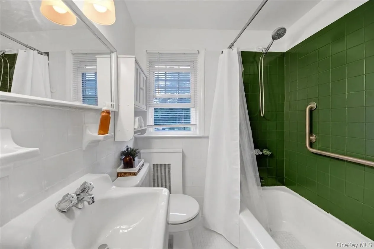 2nd floor athroom featuring green subway tile shower surround, white ceramic wall tile, built-in medicine cabinet, and a window with blinds 2nd floor athroom featuring green subway tile shower surround, white ceramic wall tile, built-in medicine cabinet, and a window with blinds