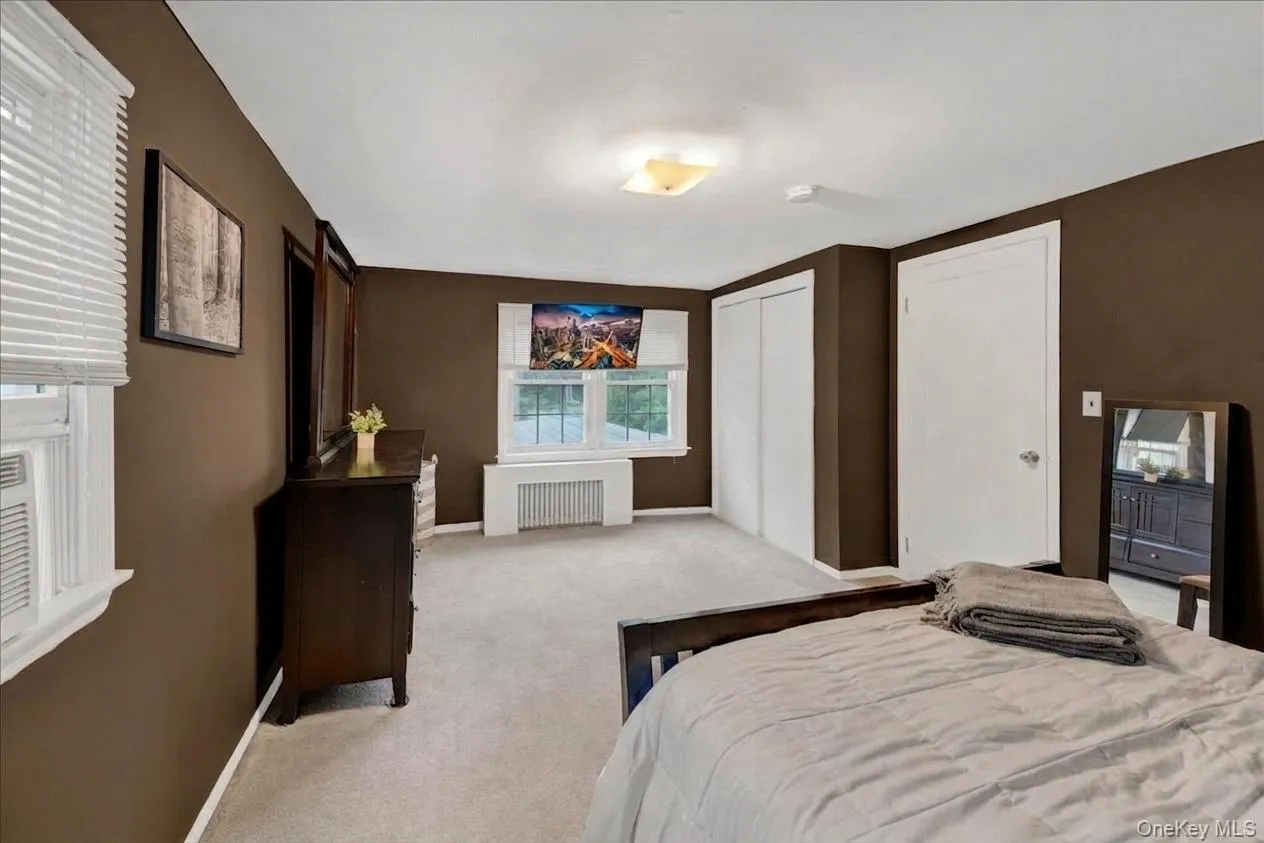 2nd floor bedroom featuring dual windows with blinds, a built-in closet with bi-fold doors, a single panel interior door, and light-colored carpeting 2nd floor bedroom featuring dual windows with blinds, a built-in closet with bi-fold doors, a single panel interior door, and light-colored carpeting