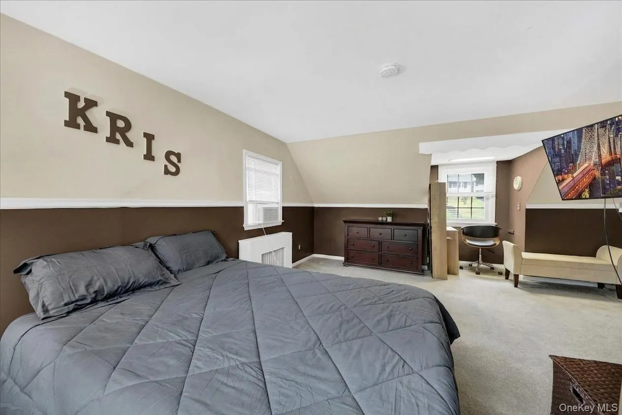 Primary bedroom on the 2nd floor with sloped ceilings and light beige walls featuring a brown wainscoting accent Primary bedroom on the 2nd floor with sloped ceilings and light beige walls featuring a brown wainscoting accent