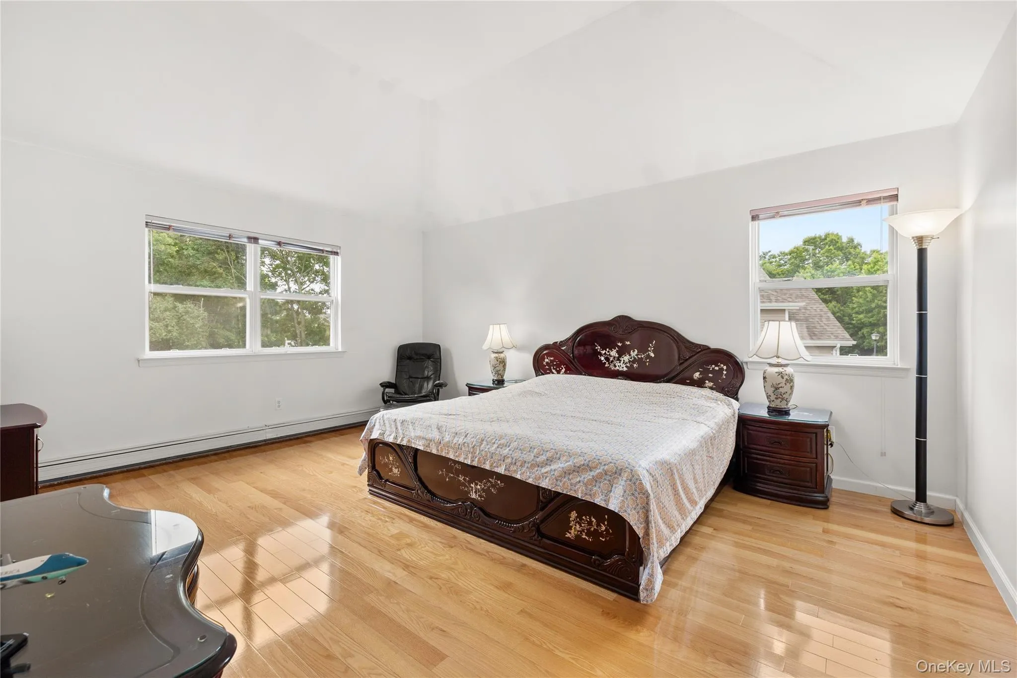 Primary bedroom featuring a vaulted ceiling and light wood-finish flooring & 2 walk-in closets. Primary bedroom featuring a vaulted ceiling and light wood-finish flooring & 2 walk-in closets.
