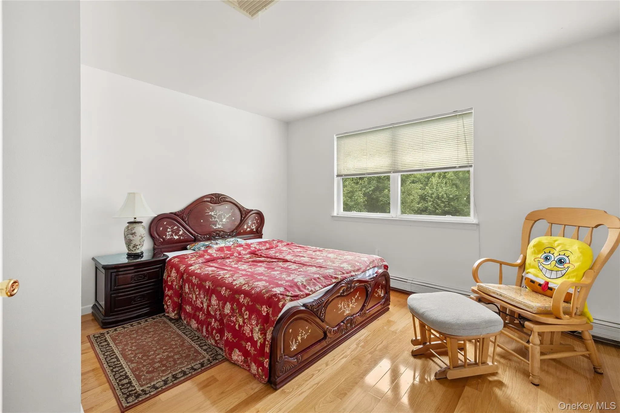 Bedroom featuring light wood-finish flooring and a window with natural light Bedroom featuring light wood-finish flooring and a window with natural light