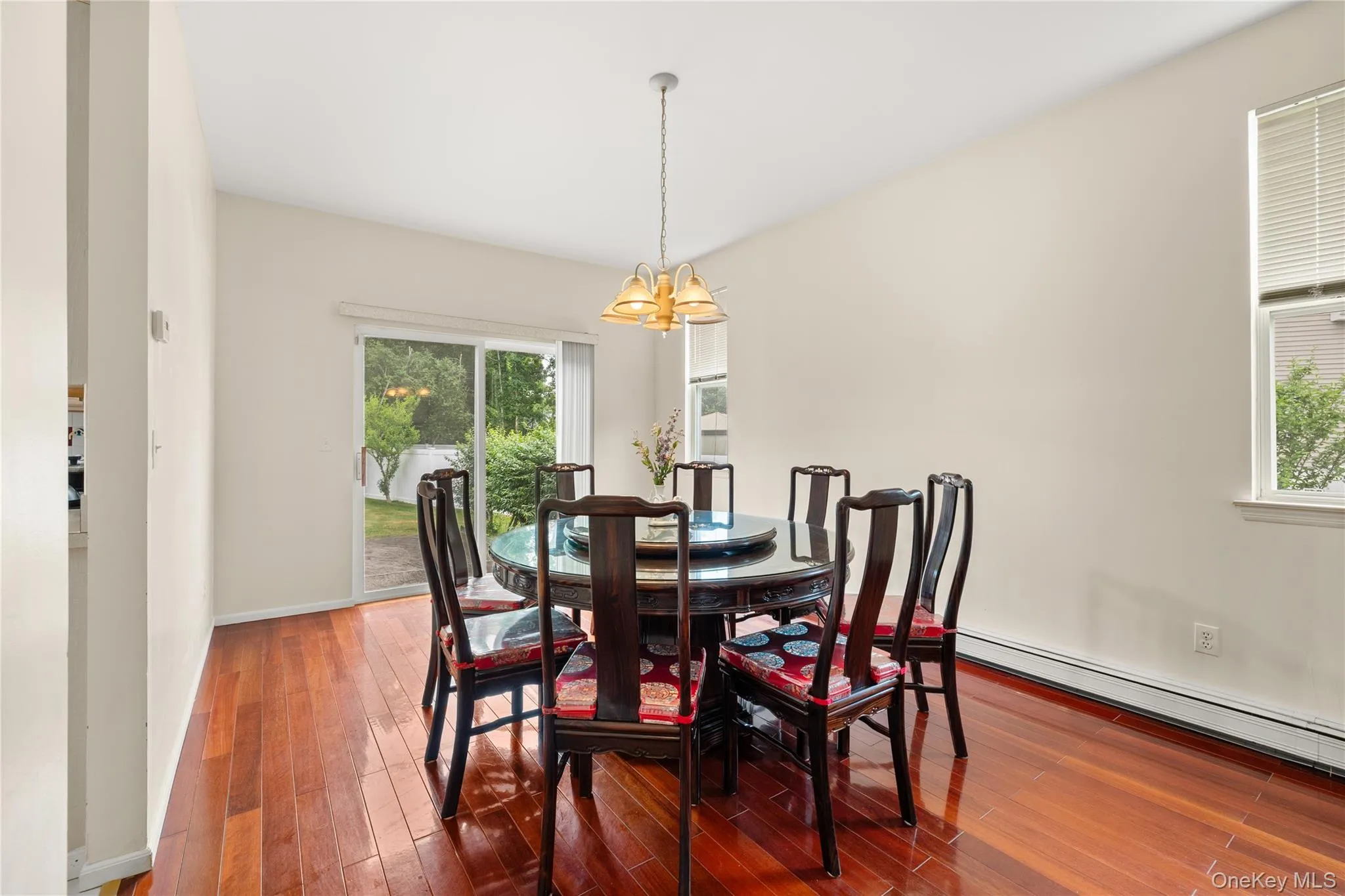 Dining area featuring wood-finish flooring, a contemporary chandelier, and a sliding glass door providing exterior access Dining area featuring wood-finish flooring, a contemporary chandelier, and a sliding glass door providing exterior access