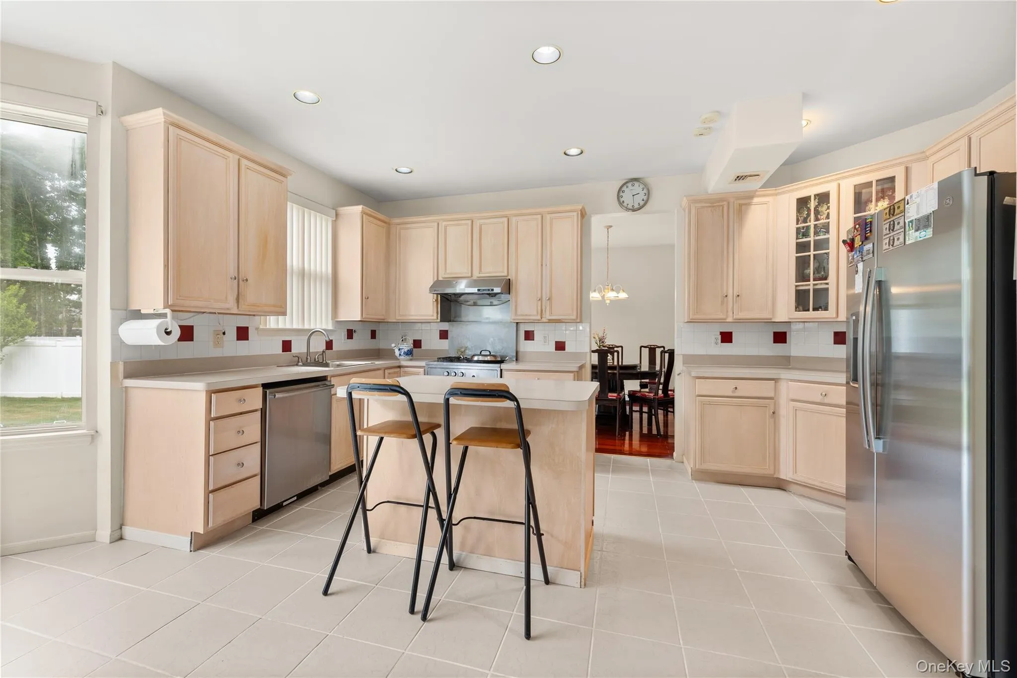Kitchen featuring light wood cabinetry, stainless steel appliances, a center island with seating, recessed lighting, and tile flooring Kitchen featuring light wood cabinetry, stainless steel appliances, a center island with seating, recessed lighting, and tile flooring