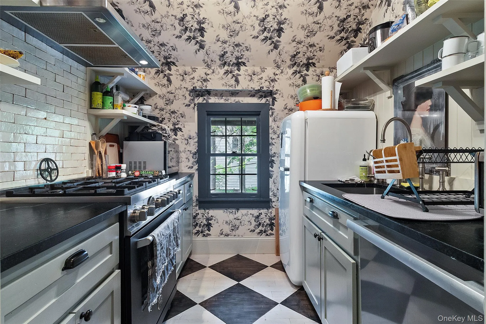 Kitchen with open shelves, wallpapered walls, gas range oven, gray cabinetry, and exhaust hood Kitchen with open shelves, wallpapered walls, gas range oven, gray cabinetry, and exhaust hood