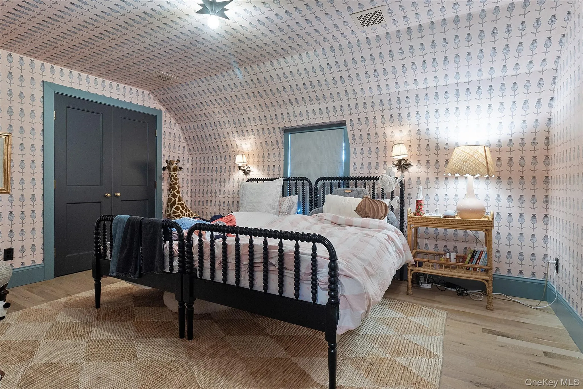 Second bedroom with wallpapered walls, light wood finished floors, a closet, and lofted ceiling. Twin beds. Second bedroom with wallpapered walls, light wood finished floors, a closet, and lofted ceiling. Twin beds.