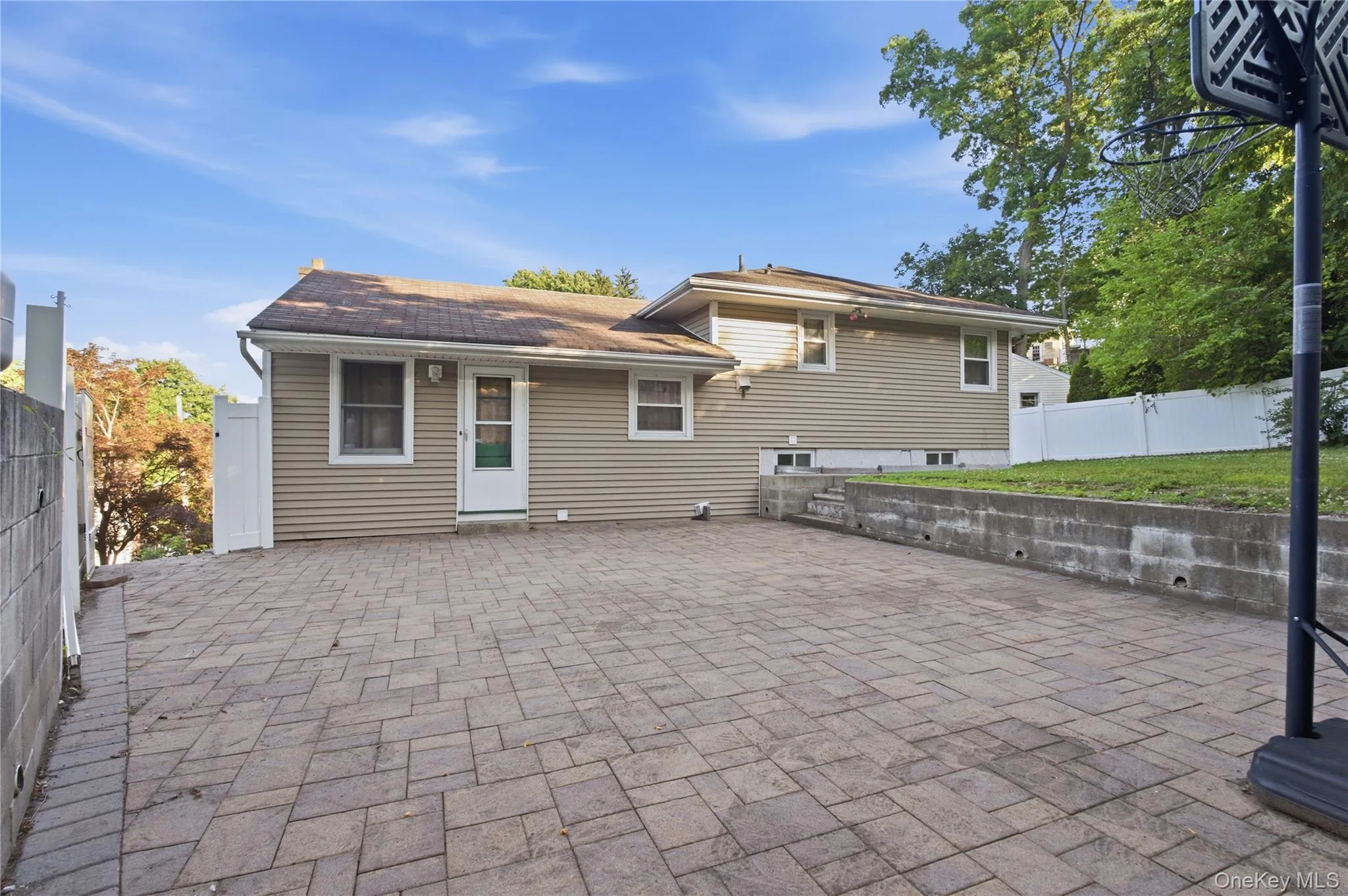 Spacious paver patio area with a privacy fence and concrete retaining wall Spacious paver patio area with a privacy fence and concrete retaining wall
