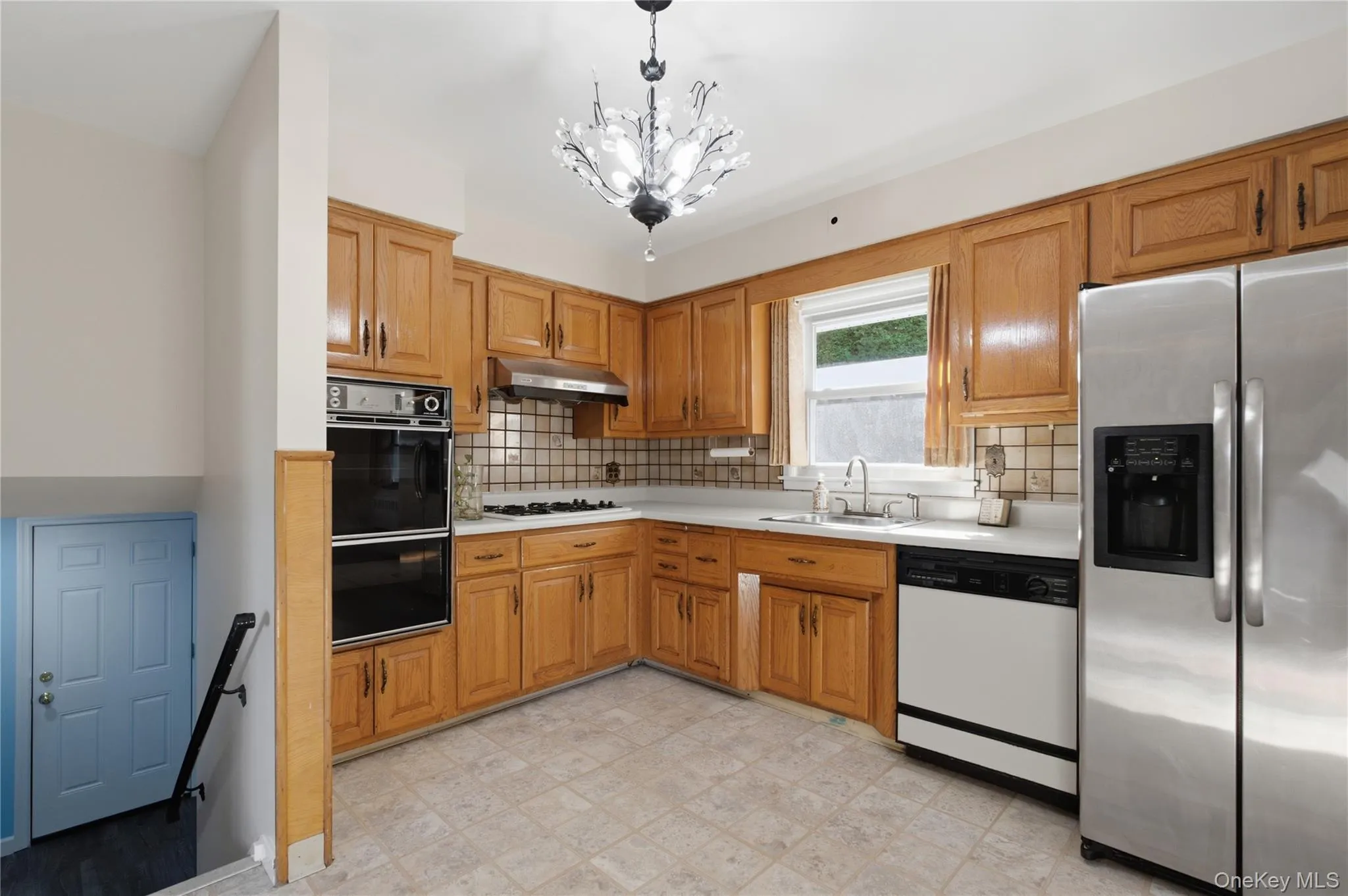 Kitchen featuring wood cabinetry, light countertops, and tile flooring Kitchen featuring wood cabinetry, light countertops, and tile flooring