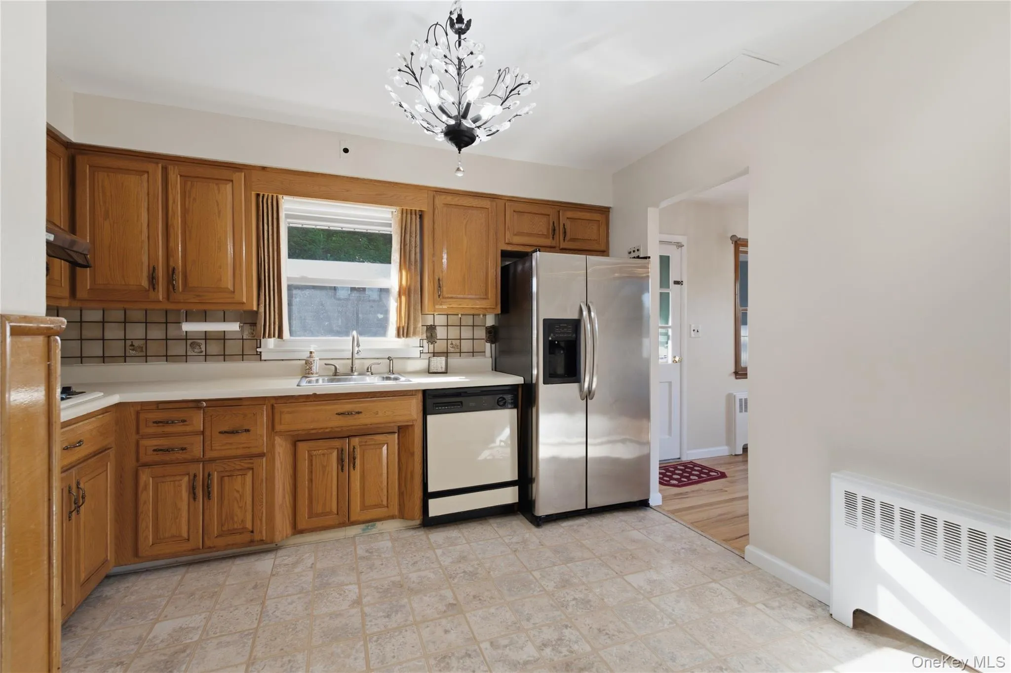 Kitchen featuring wood cabinetry, a stainless steel refrigerator, and tiled flooring Kitchen featuring wood cabinetry, a stainless steel refrigerator, and tiled flooring