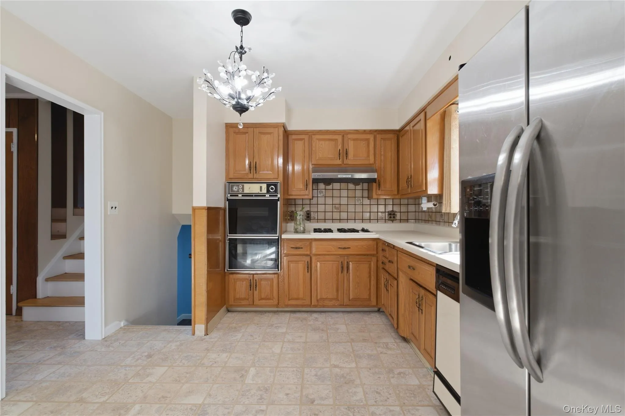 Kitchen featuring light wood cabinetry, stone-look tile flooring, and a built-in double oven Kitchen featuring light wood cabinetry, stone-look tile flooring, and a built-in double oven