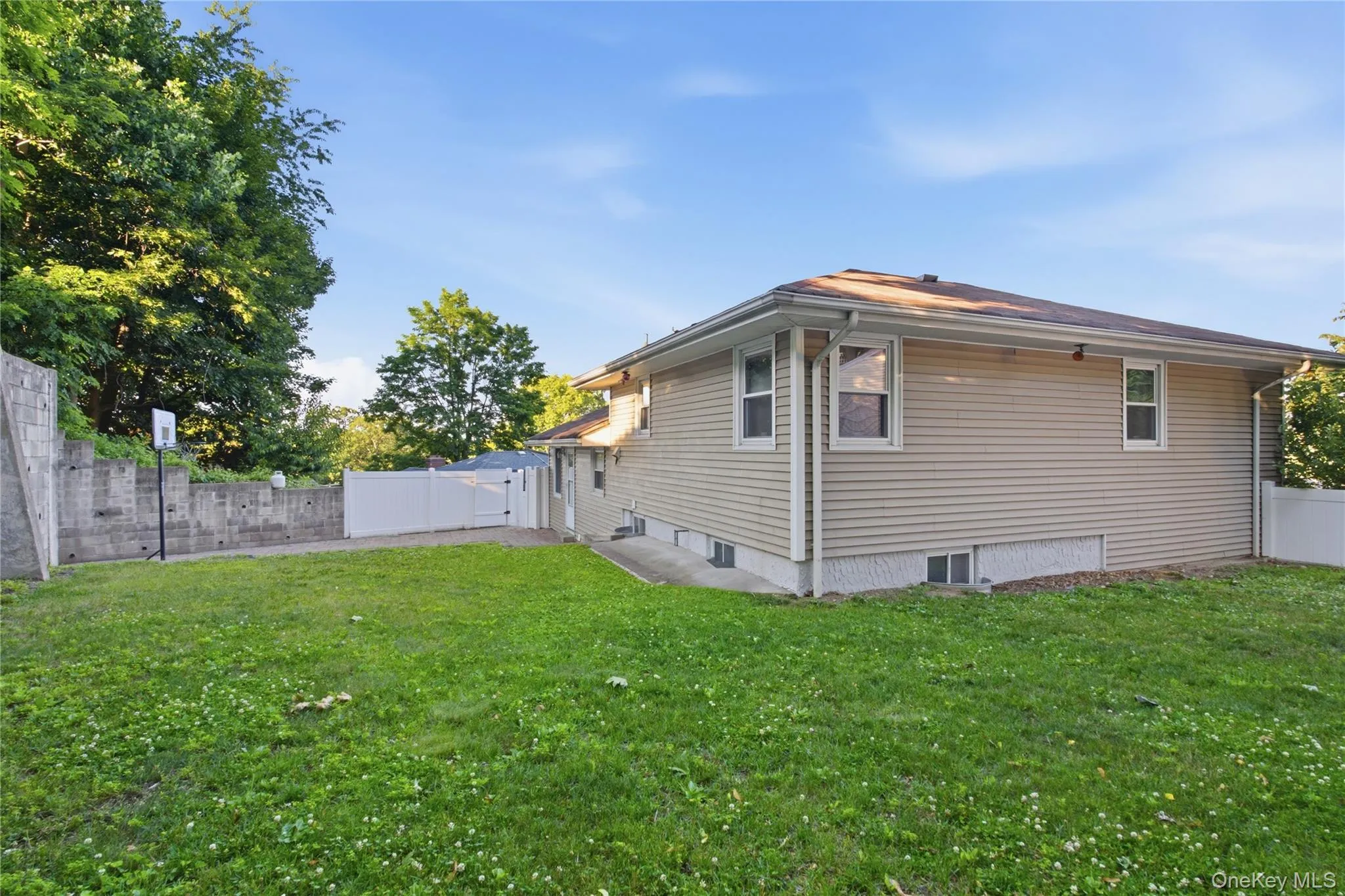 Expansive side yard featuring a manicured lawn, concrete retaining wall, and white vinyl fencing Expansive side yard featuring a manicured lawn, concrete retaining wall, and white vinyl fencing