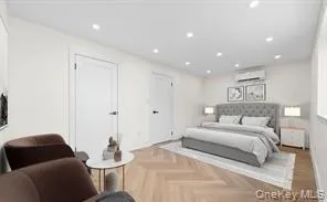 Bedroom 1 with walk in closest. Bright room featuring recessed lighting, herringbone wood-finish flooring, white walls, and a wall-mounted climate control unit Bedroom 1 with walk in closest. Bright room featuring recessed lighting, herringbone wood-finish flooring, white walls, and a wall-mounted climate control unit