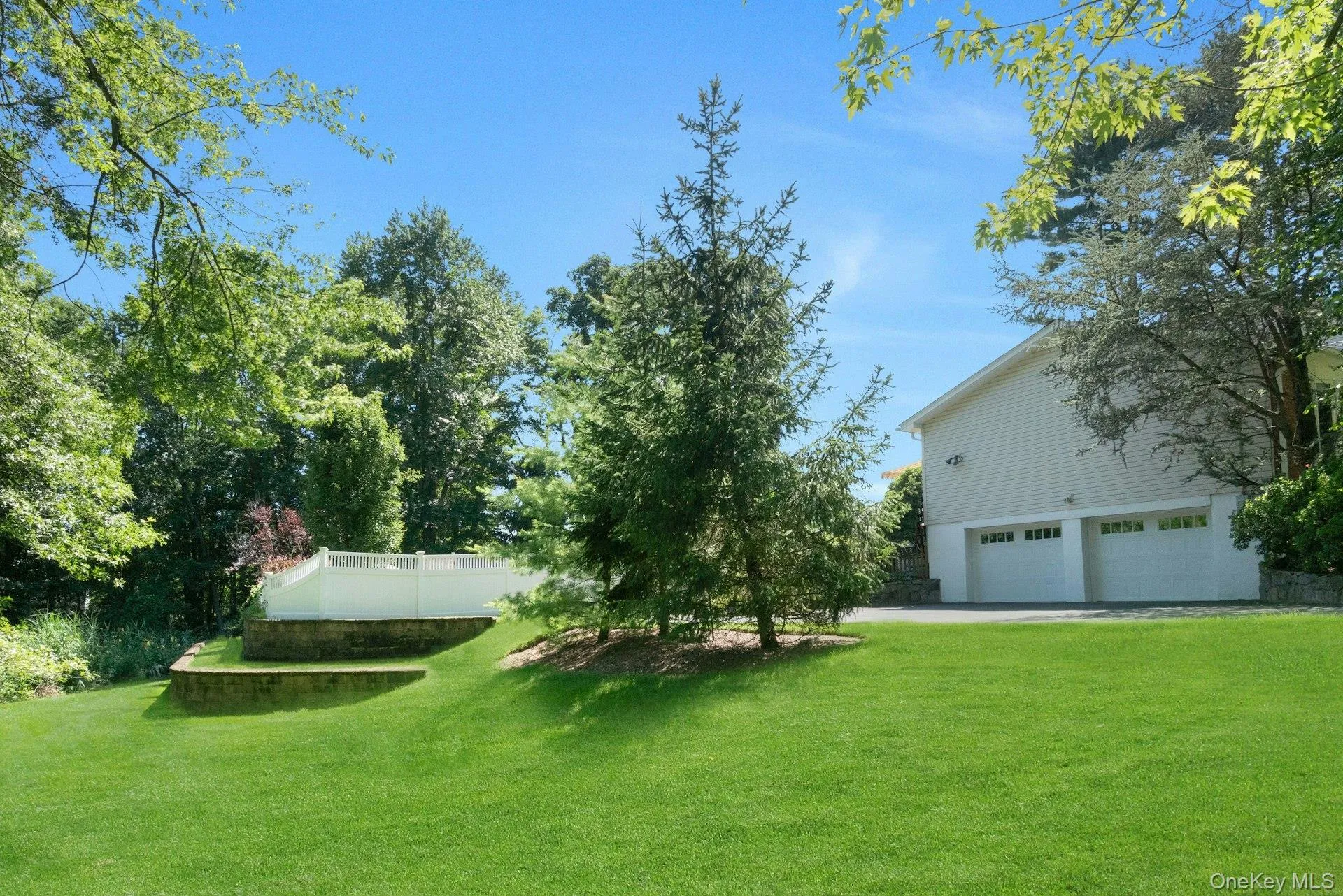 View of lower side yard with retaining walls and lined with ornamental grass. View of lower side yard with retaining walls and lined with ornamental grass.