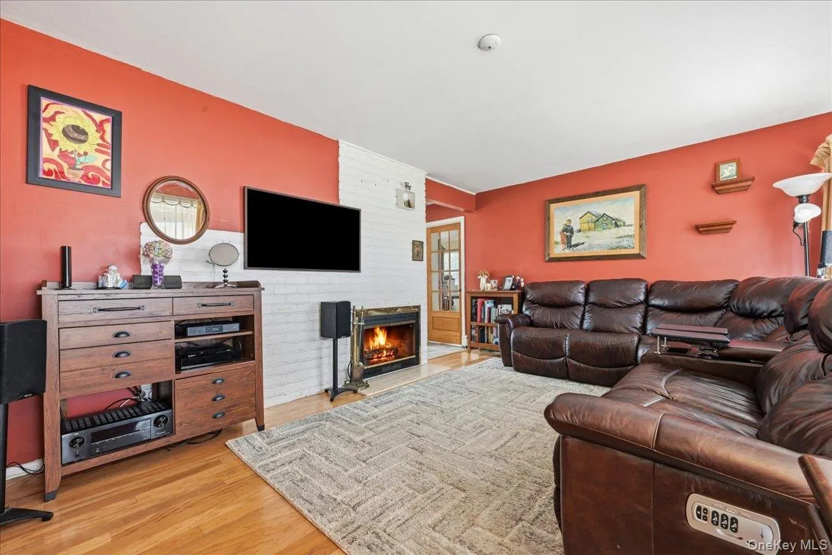 Living area featuring hardwood flooring and a white painted brick fireplace Living area featuring hardwood flooring and a white painted brick fireplace