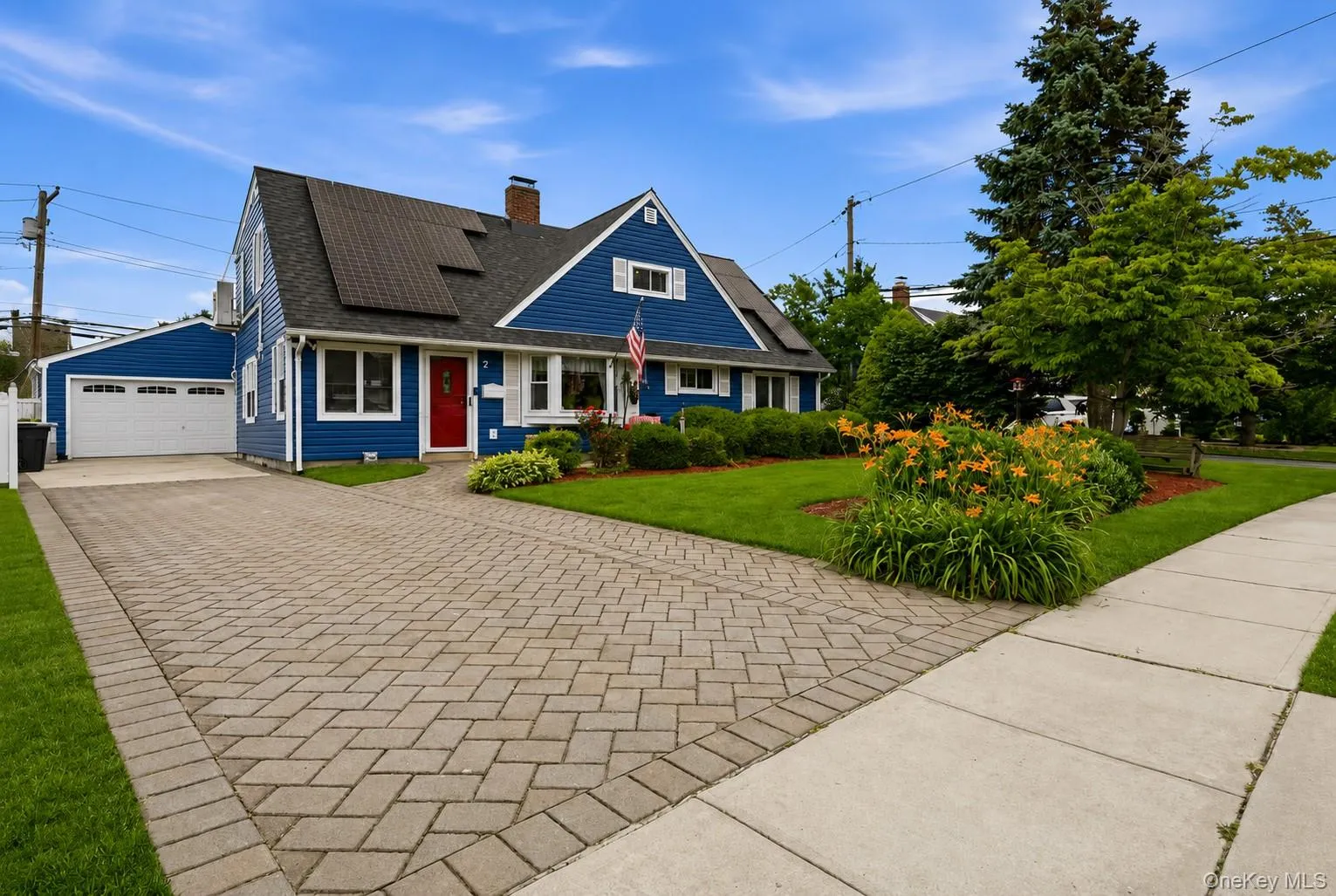 Blue siding residence featuring a red entry door, white trim, and solar panels on the roof Blue siding residence featuring a red entry door, white trim, and solar panels on the roof