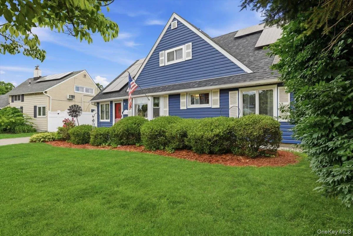 Blue vinyl siding exterior with white window trim and shutters, a dark shingle roof, and solar panels Blue vinyl siding exterior with white window trim and shutters, a dark shingle roof, and solar panels