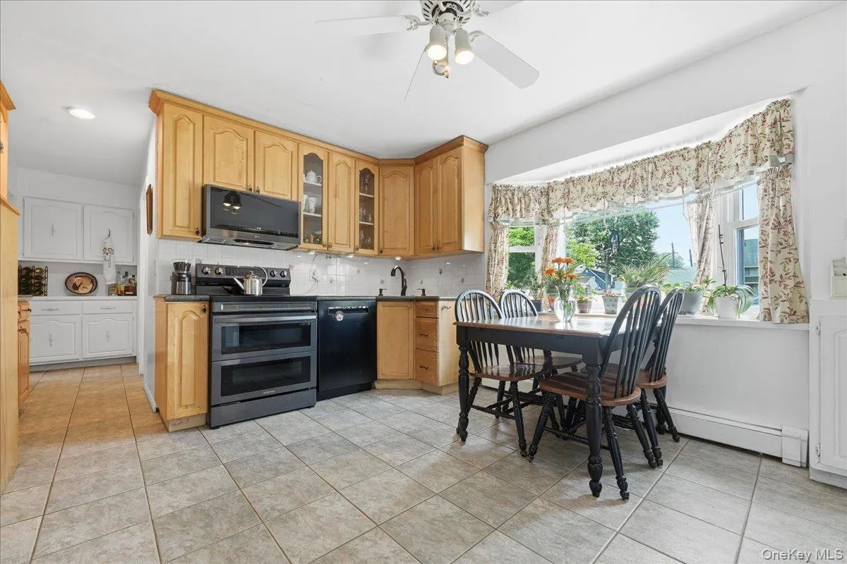 Kitchen featuring light wood cabinetry, black appliances, and a tile backsplash Kitchen featuring light wood cabinetry, black appliances, and a tile backsplash
