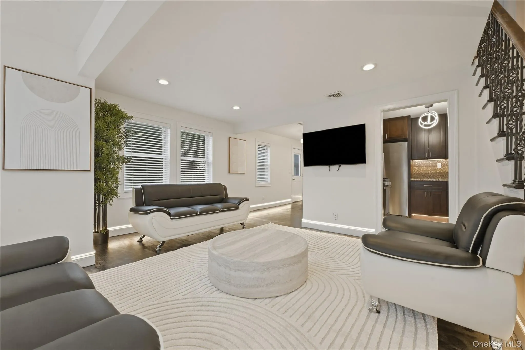 Spacious living area featuring dark wood-finish flooring, recessed lighting, and white walls Spacious living area featuring dark wood-finish flooring, recessed lighting, and white walls