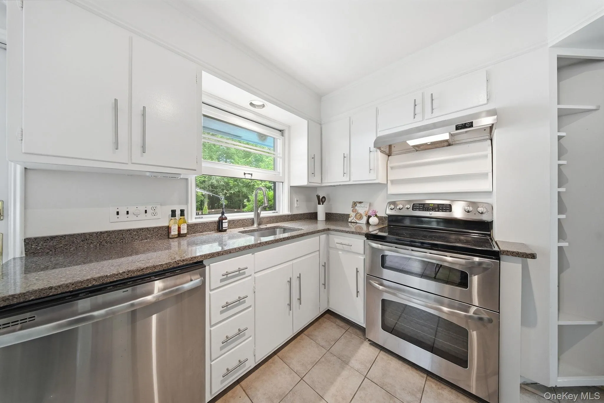 Kitchen featuring white cabinetry, dark speckled countertops, stainless steel appliances, and tiled flooring Kitchen featuring white cabinetry, dark speckled countertops, stainless steel appliances, and tiled flooring