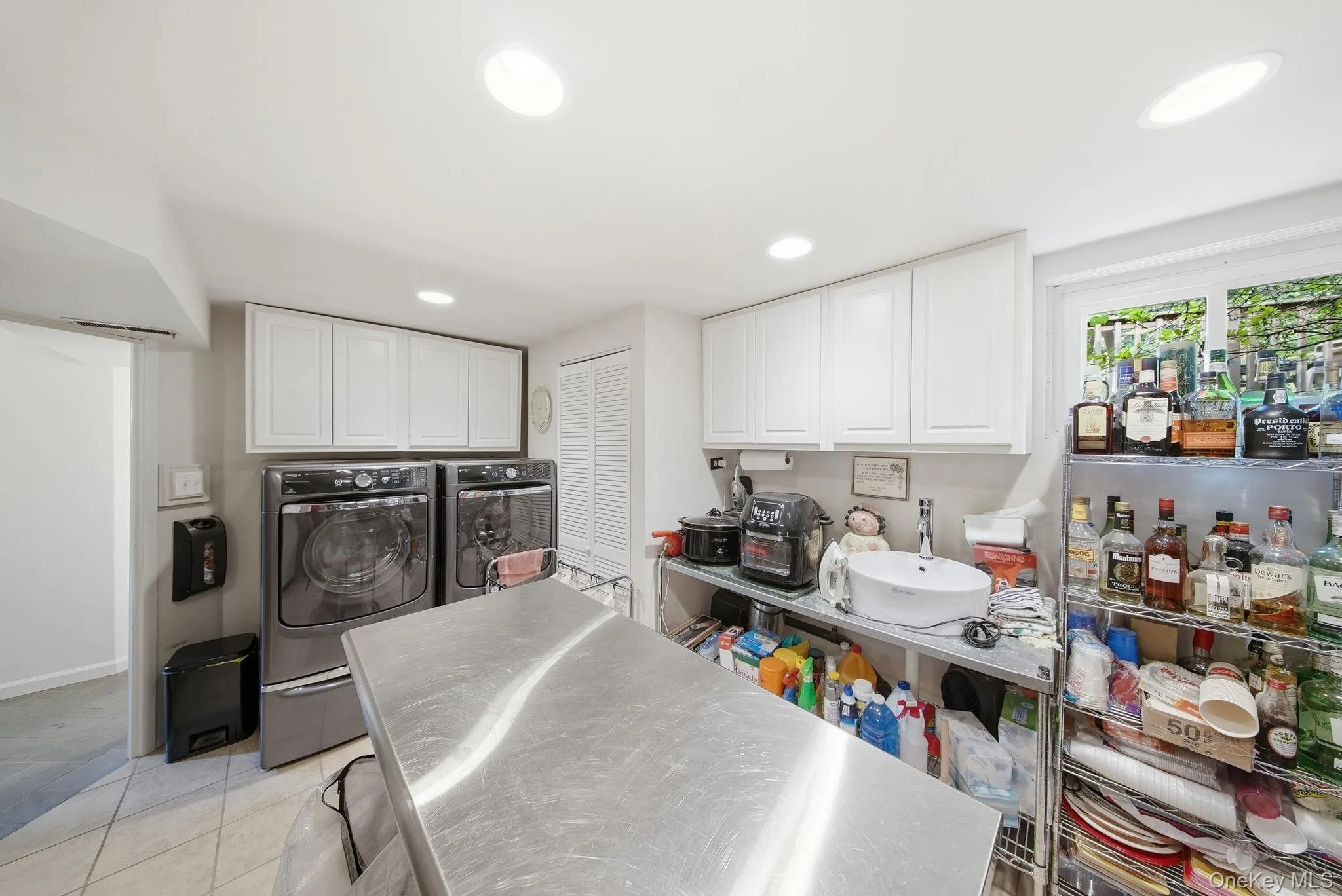 Functional laundry 2nd Kitchen area featuring white upper cabinetry and a stainless steel prep island Functional laundry 2nd Kitchen area featuring white upper cabinetry and a stainless steel prep island