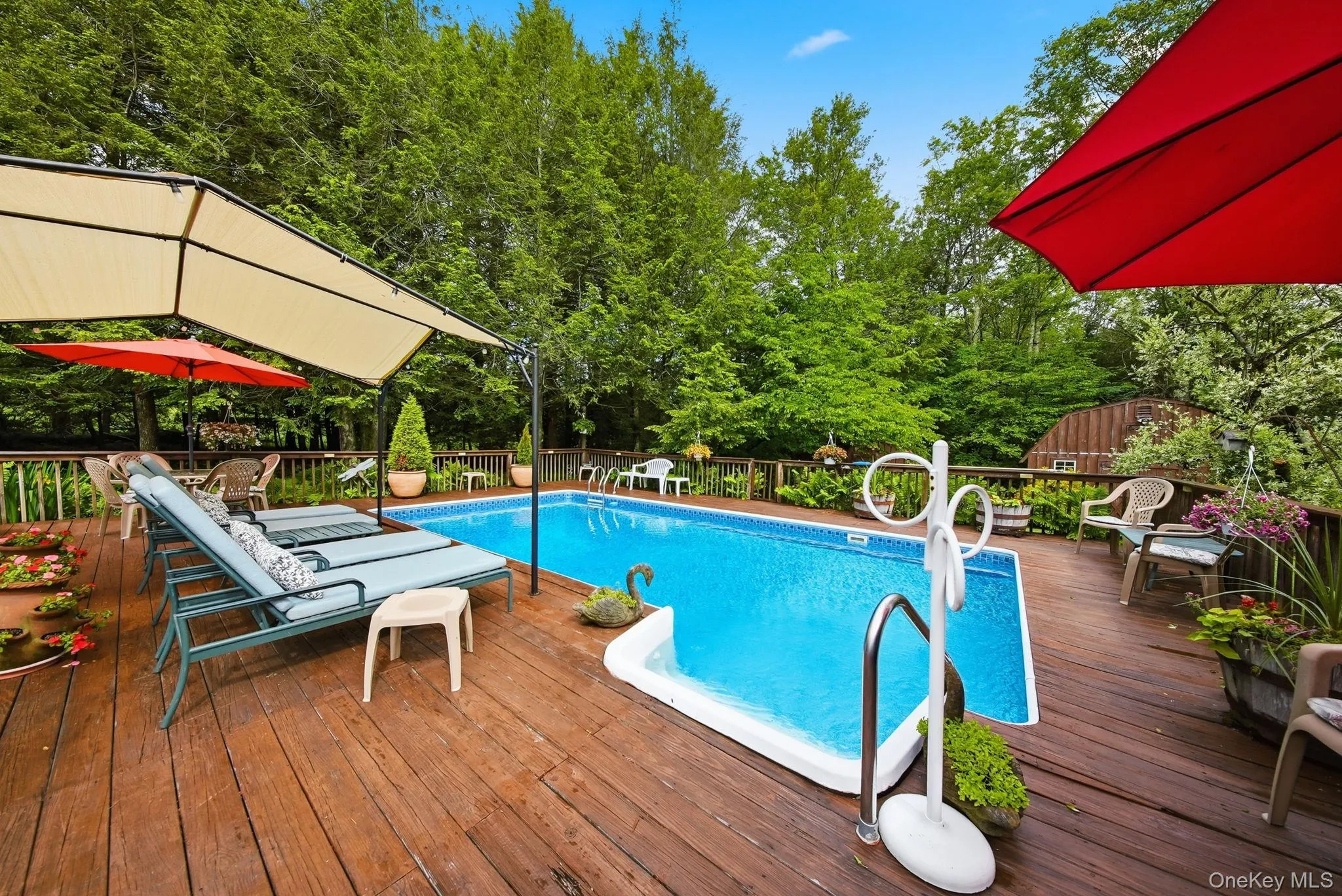 Inground swimming pool surrounded by a large wood-finish deck with a wood railing Inground swimming pool surrounded by a large wood-finish deck with a wood railing