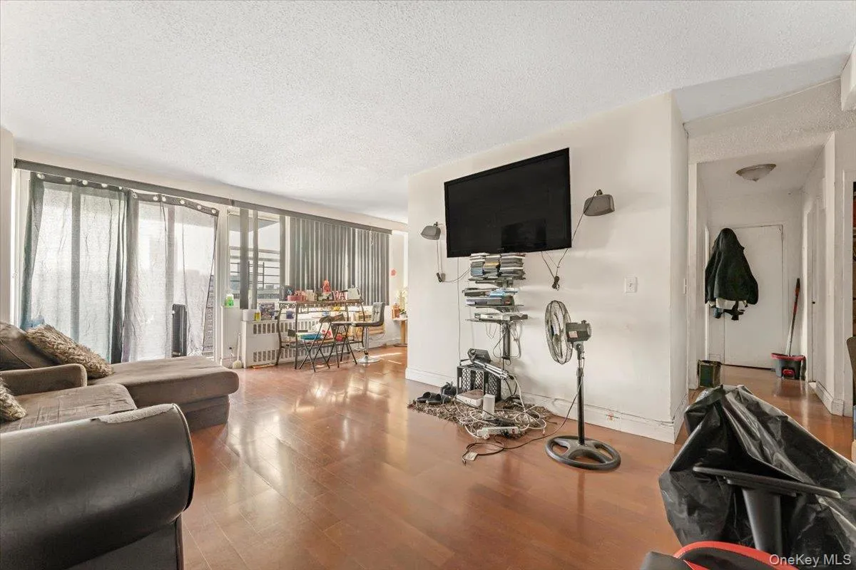 Living area with a textured ceiling, wood finished floors, baseboards, and radiator heating unit Living area with a textured ceiling, wood finished floors, baseboards, and radiator heating unit