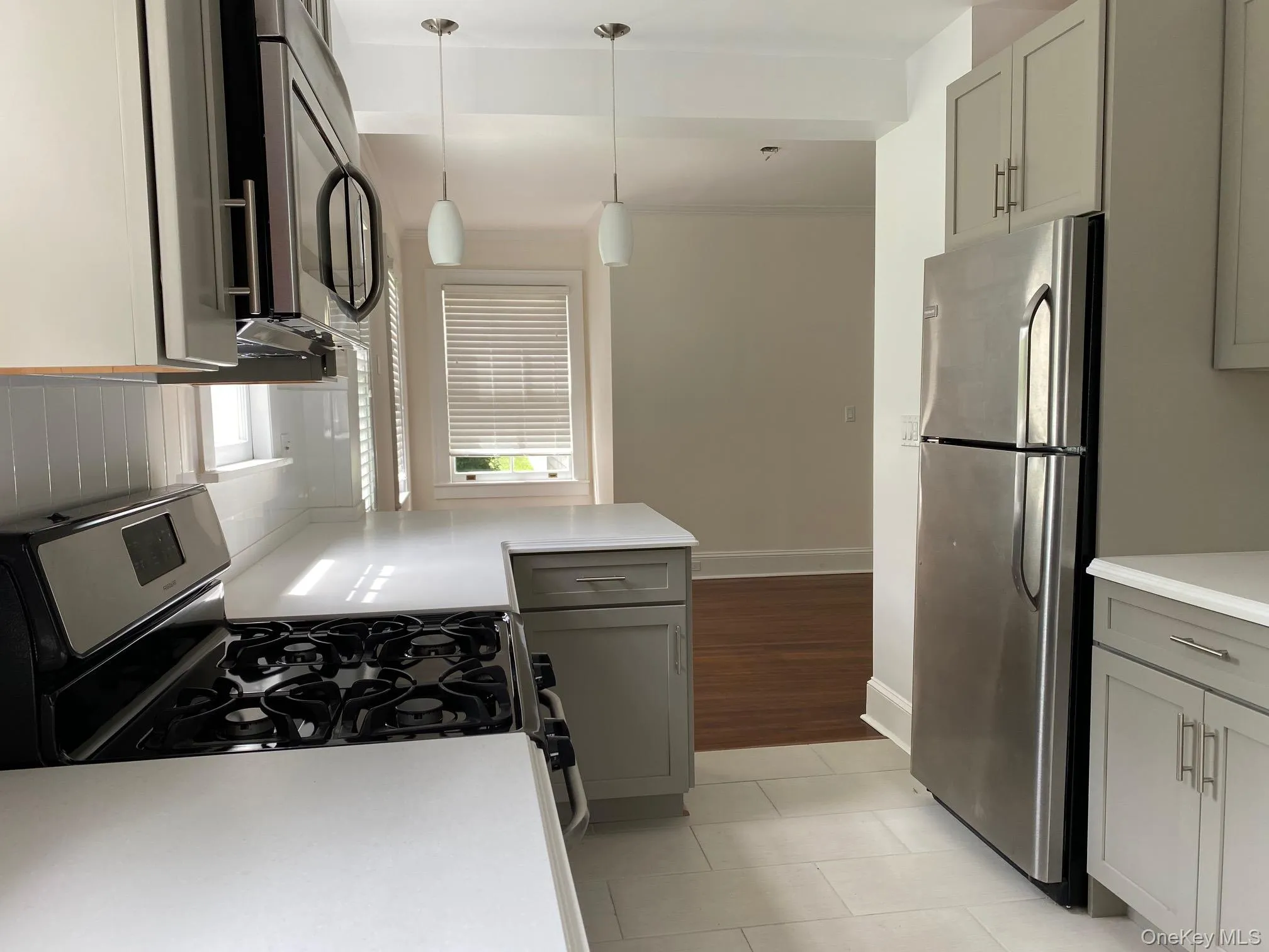 Kitchen featuring light-toned cabinetry, stainless steel appliances, a gas range, white countertops, and a white subway tile backsplash Kitchen featuring light-toned cabinetry, stainless steel appliances, a gas range, white countertops, and a white subway tile backsplash