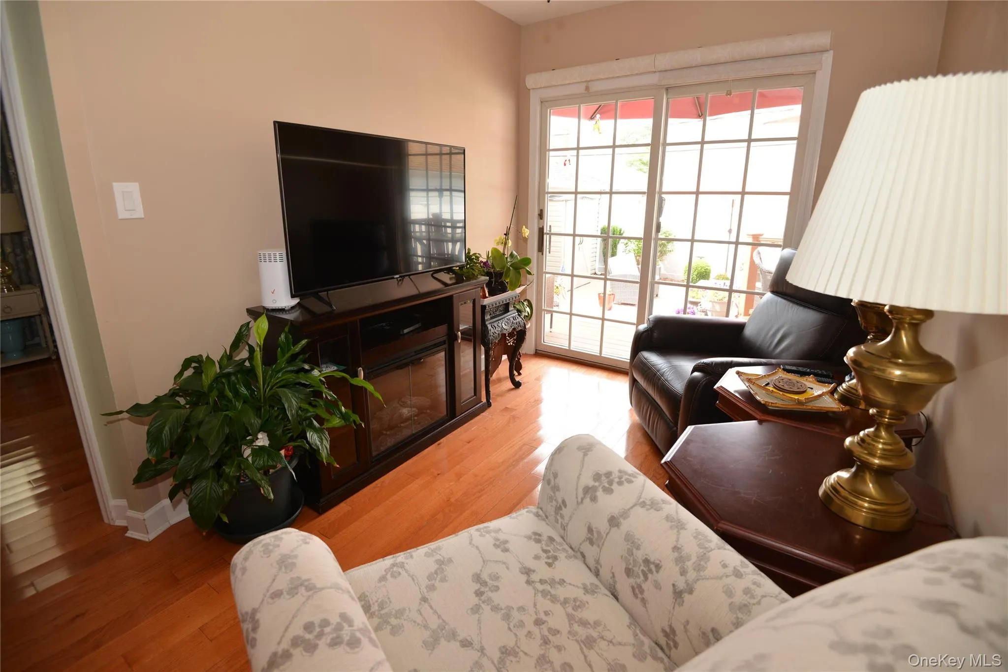 Living area featuring wood-finish flooring, light neutral wall paint, and a sliding glass door with grid detailing Living area featuring wood-finish flooring, light neutral wall paint, and a sliding glass door with grid detailing