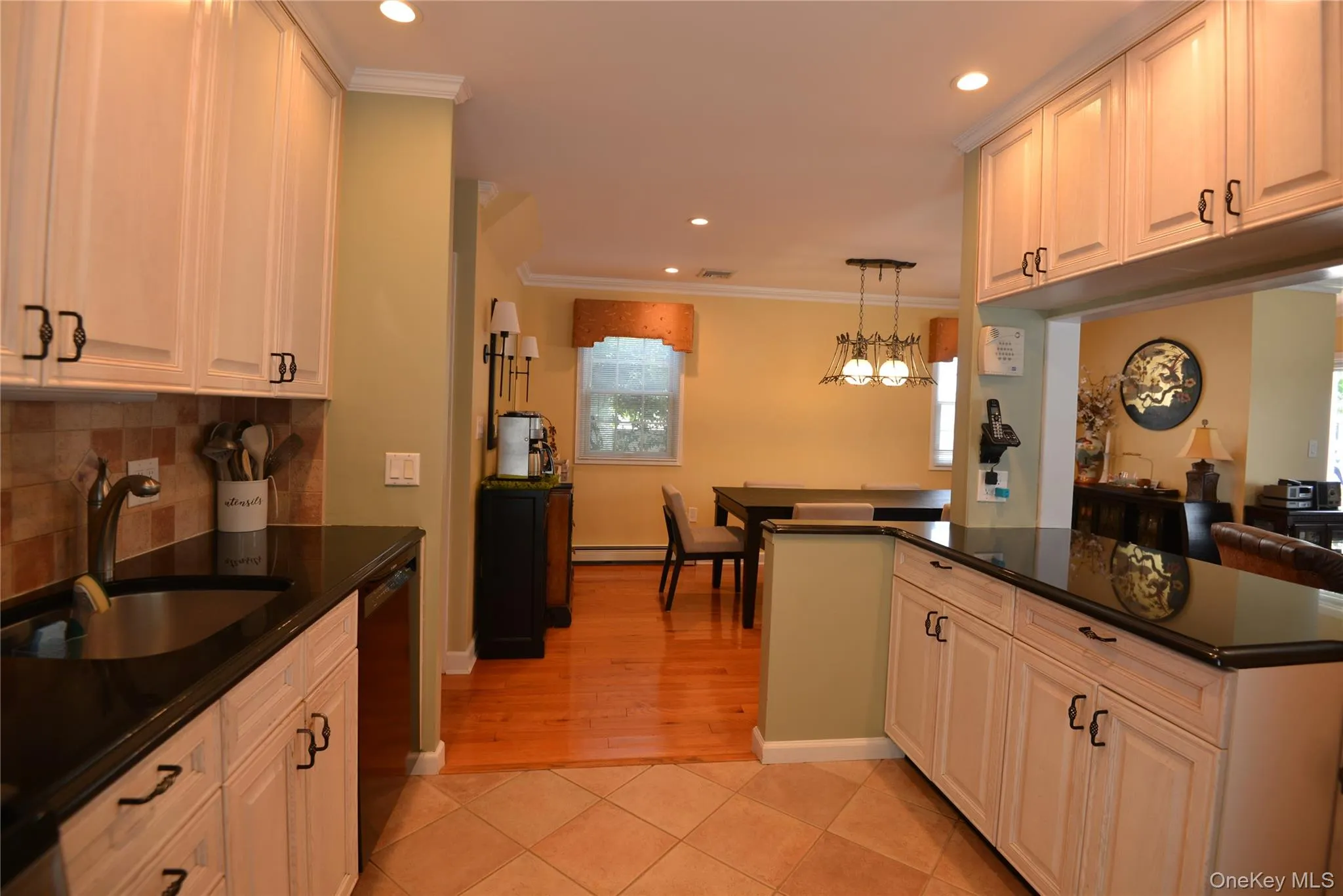 Kitchen featuring light-toned cabinetry, dark countertops, and a stainless steel sink with a gooseneck faucet Kitchen featuring light-toned cabinetry, dark countertops, and a stainless steel sink with a gooseneck faucet