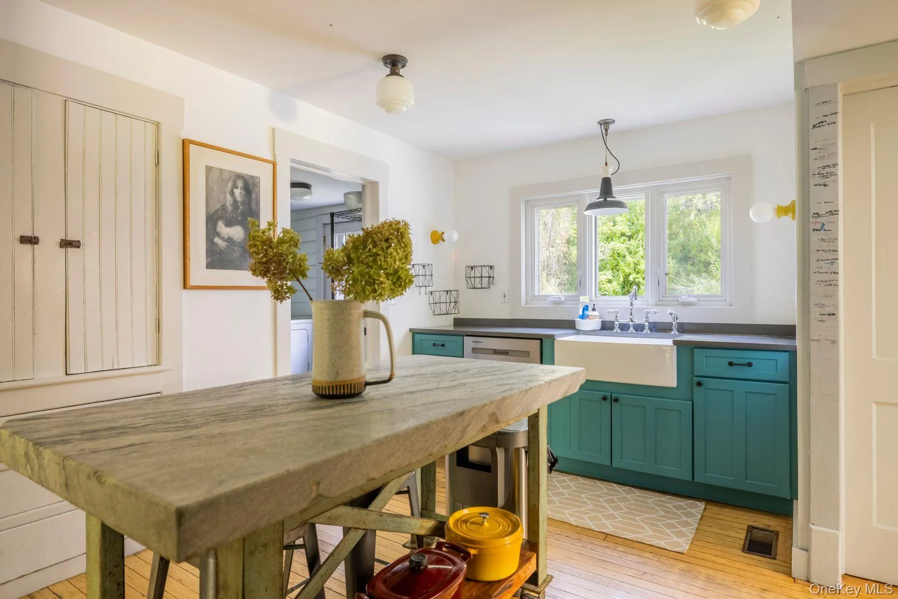 Built-in storage cabinetry, wood-finish flooring, apron-front sink, teal lower cabinetry, and fixed window over sink Built-in storage cabinetry, wood-finish flooring, apron-front sink, teal lower cabinetry, and fixed window over sink