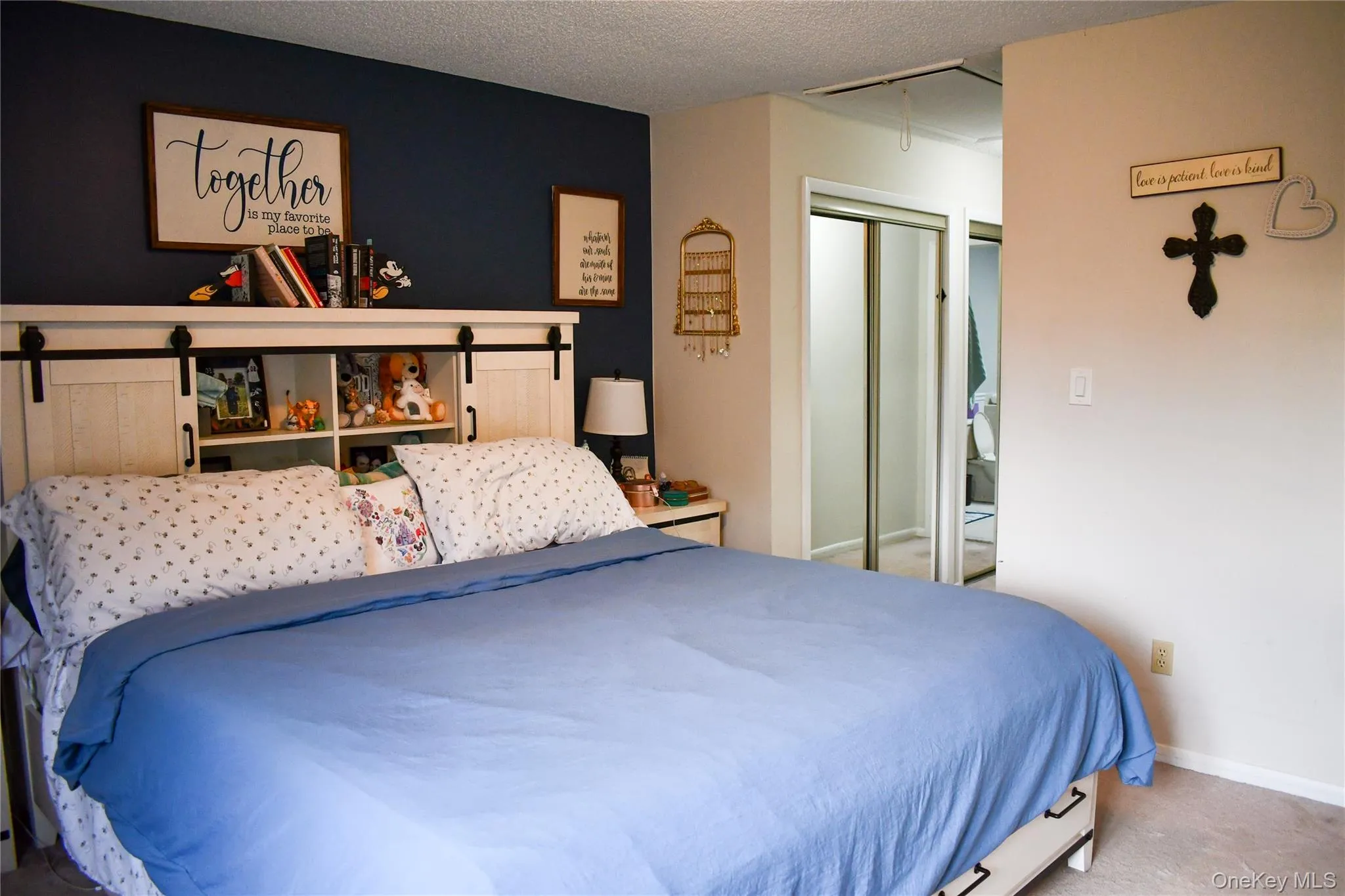 Bedroom featuring a built-in headboard with integrated shelving and sliding barn-door style cabinet fronts Bedroom featuring a built-in headboard with integrated shelving and sliding barn-door style cabinet fronts
