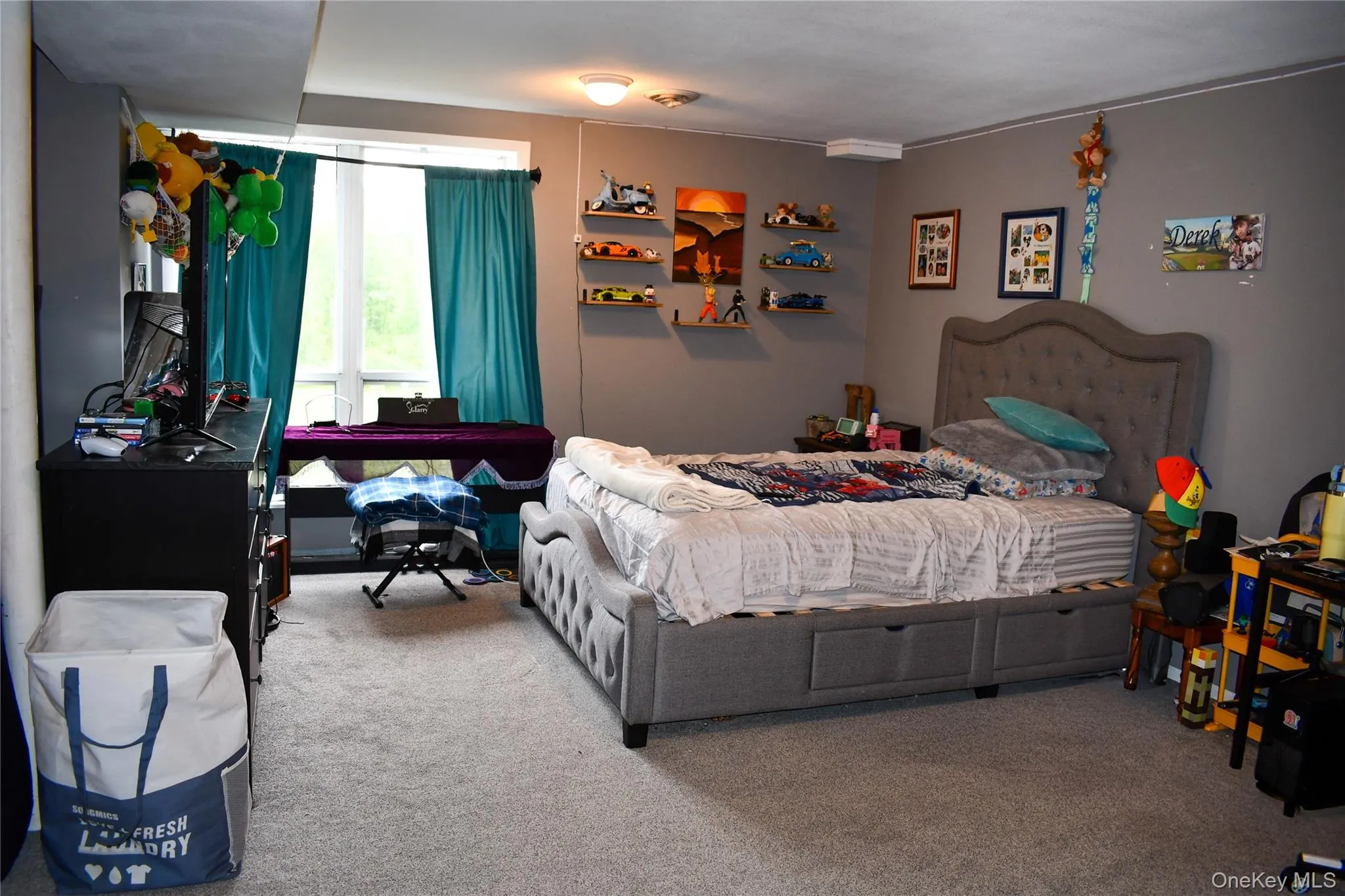 Carpeted room featuring a large window, neutral wall paint, and a built-in overhead light fixture Carpeted room featuring a large window, neutral wall paint, and a built-in overhead light fixture