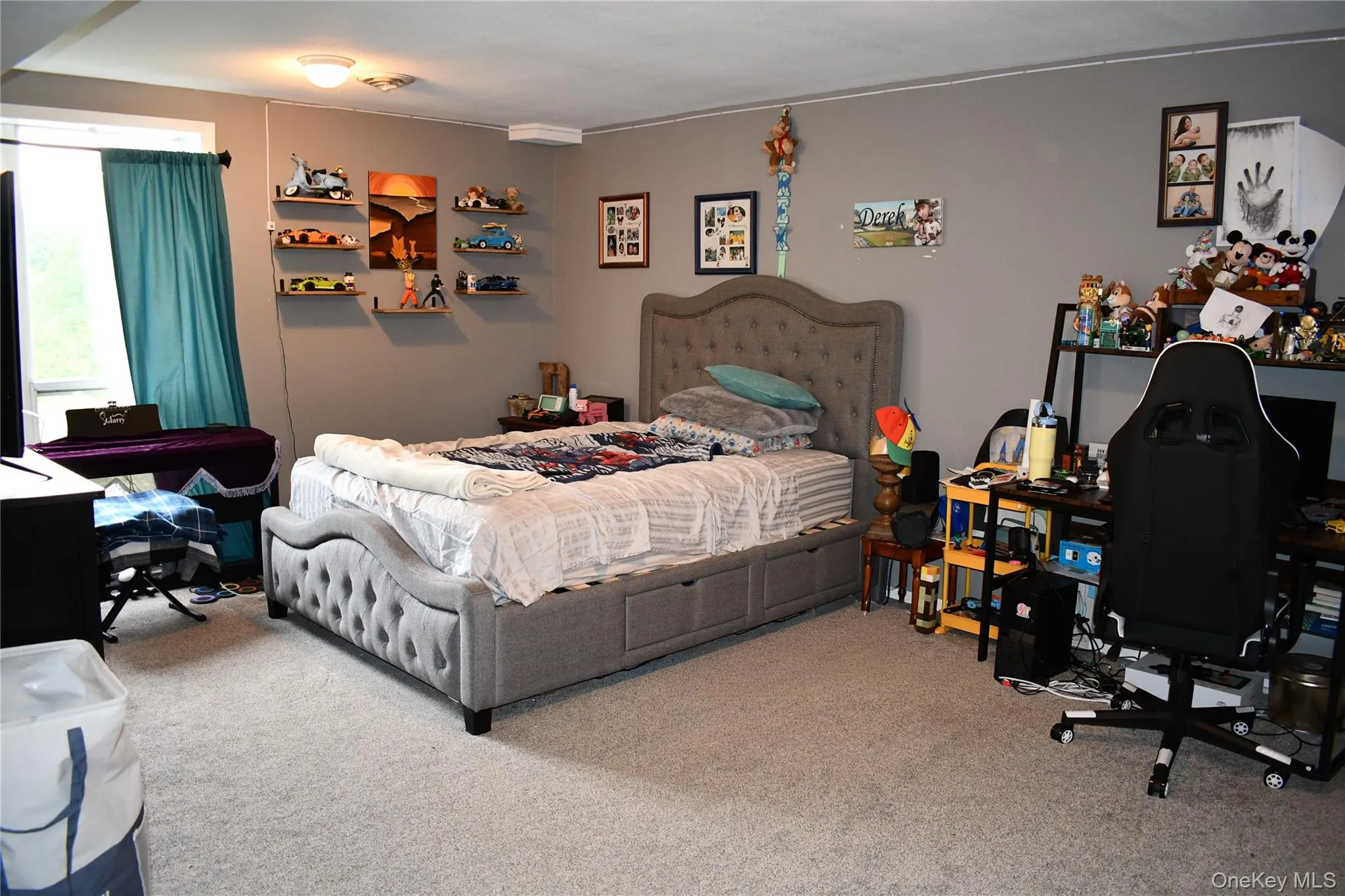 Carpeted bedroom featuring a window with teal drapes, wall-mounted shelving, and a ceiling light fixture Carpeted bedroom featuring a window with teal drapes, wall-mounted shelving, and a ceiling light fixture