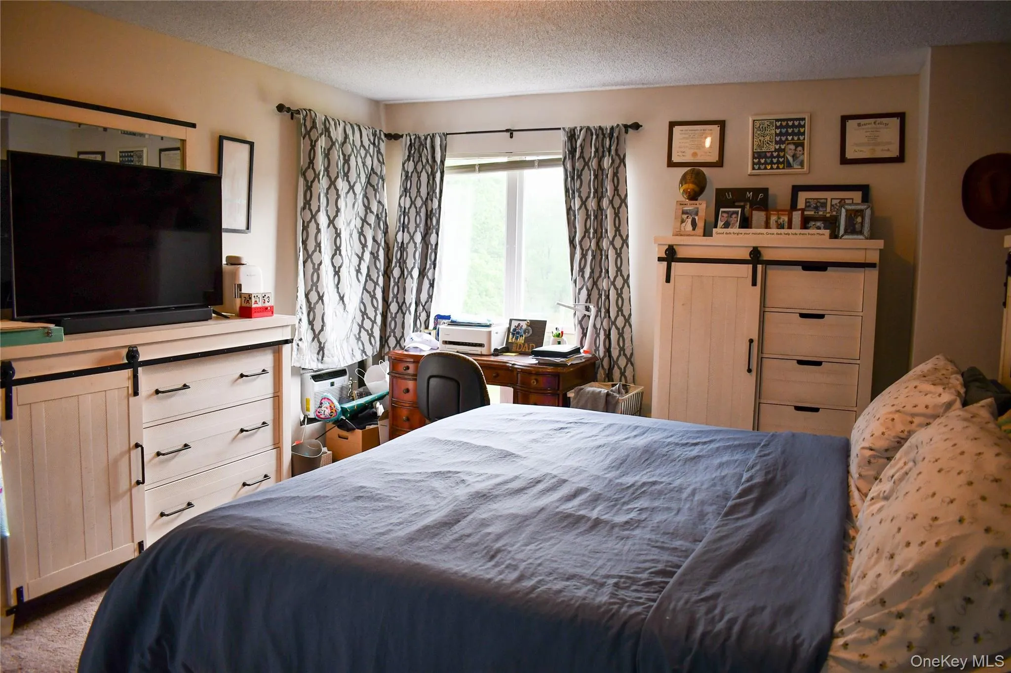 Bedroom featuring a large window, neutral wall paint, and textured ceiling Bedroom featuring a large window, neutral wall paint, and textured ceiling
