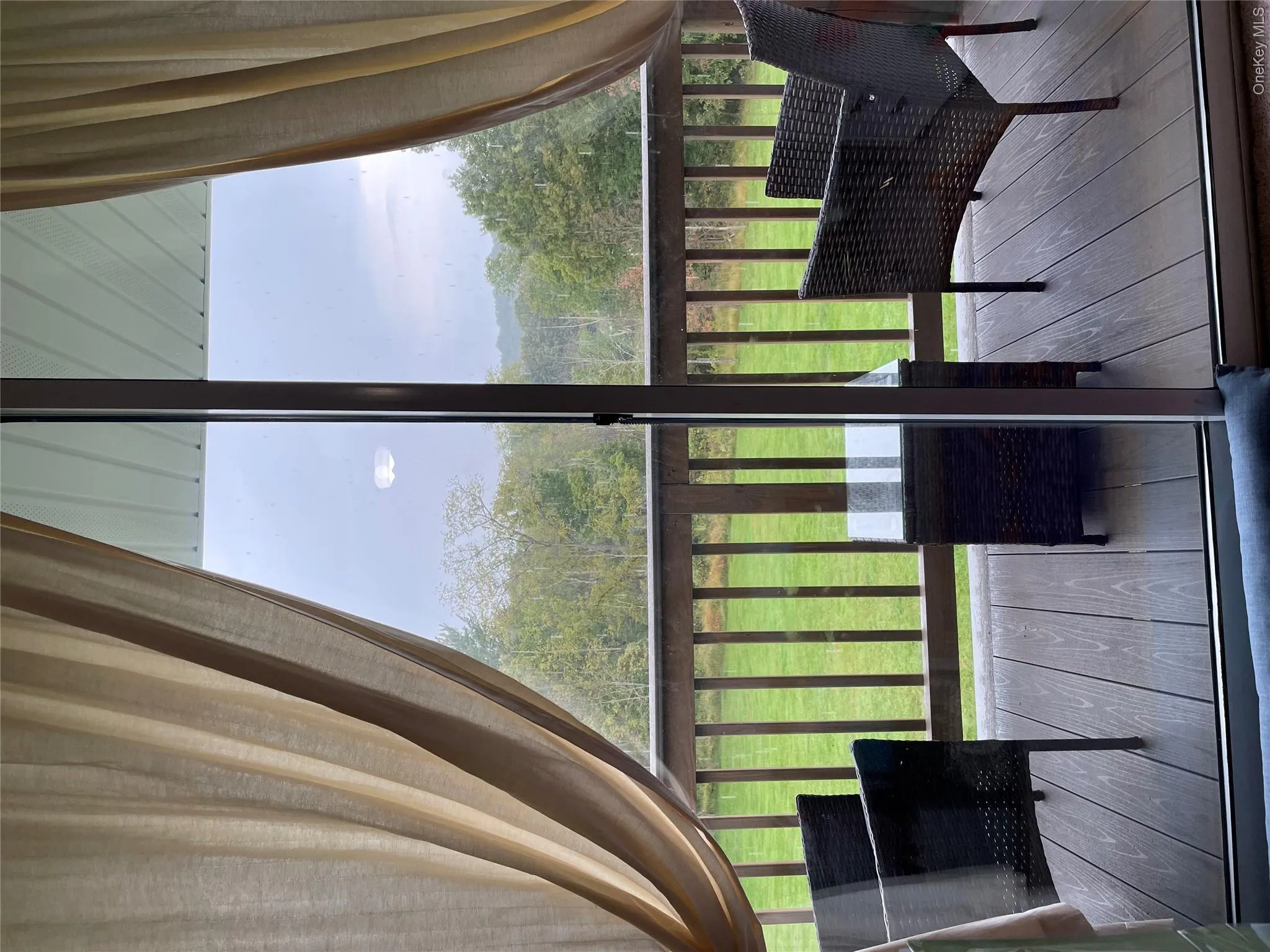 Sliding glass door opening to a private exterior deck featuring wood-finish flooring and a wood railing Sliding glass door opening to a private exterior deck featuring wood-finish flooring and a wood railing