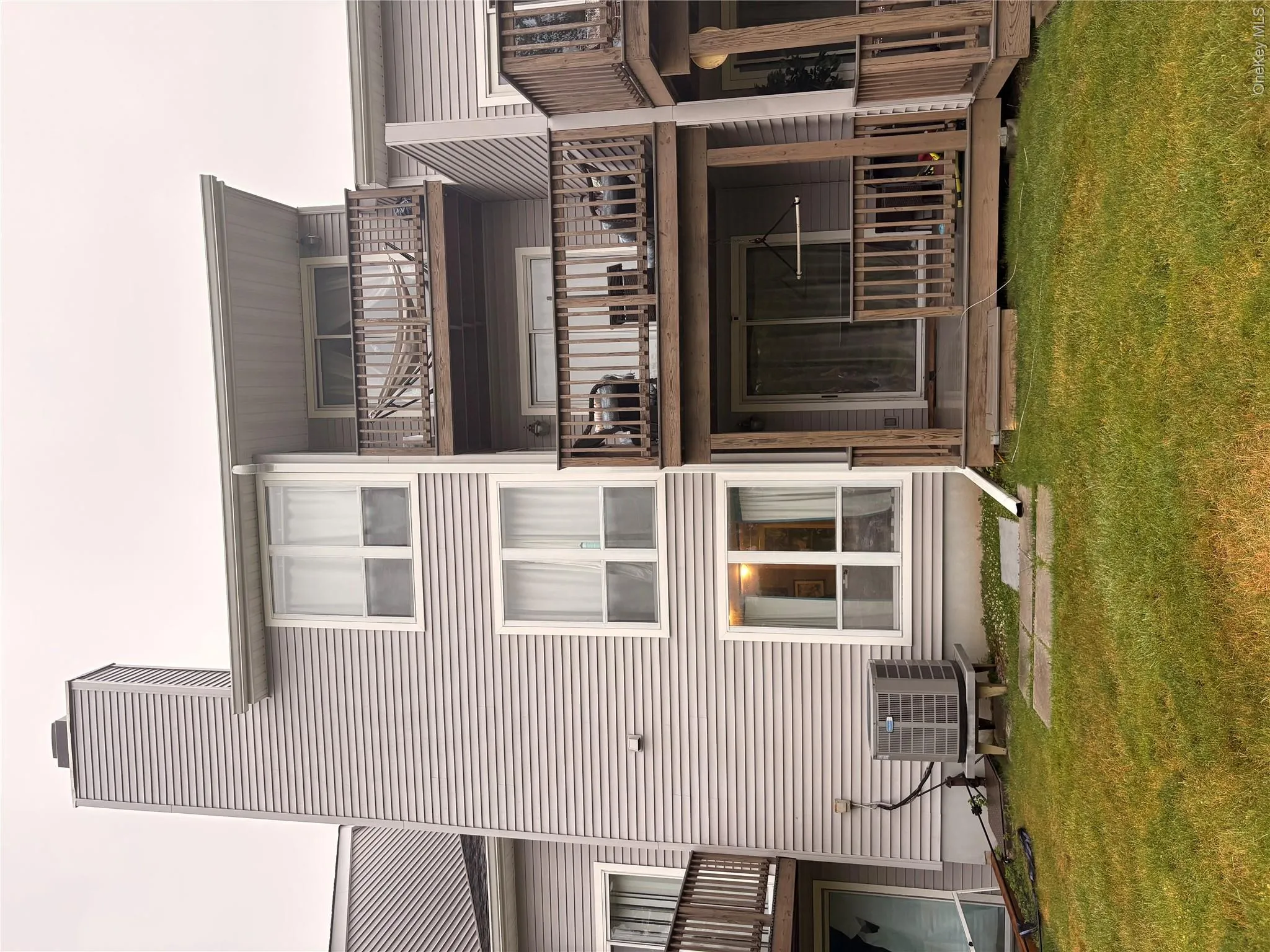 Multi-level exterior featuring light-colored siding, a prominent chimney, and a ground-level patio Multi-level exterior featuring light-colored siding, a prominent chimney, and a ground-level patio