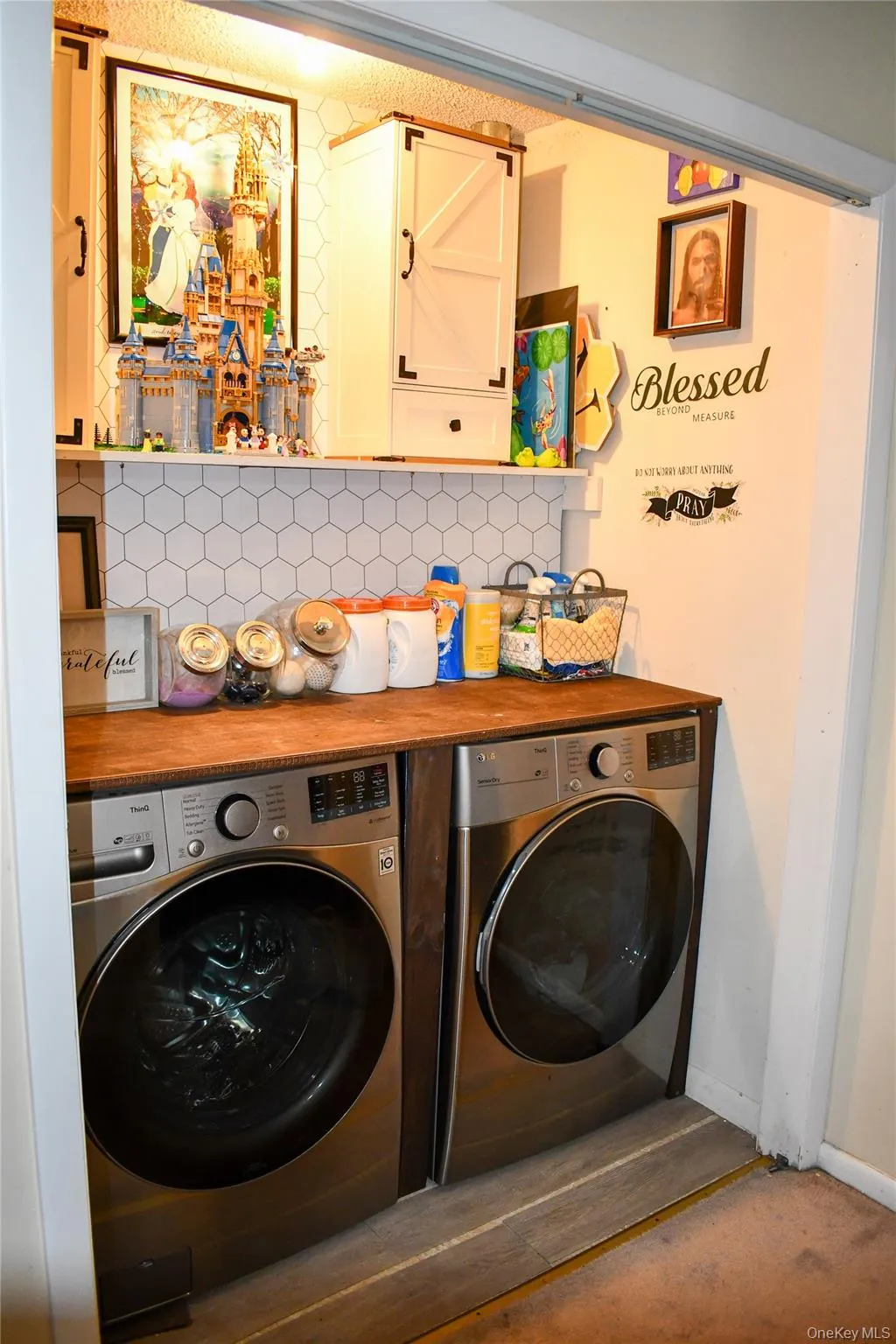 Dedicated laundry area featuring a wood-finish countertop, hexagonal tile backsplash, and built-in upper cabinetry Dedicated laundry area featuring a wood-finish countertop, hexagonal tile backsplash, and built-in upper cabinetry