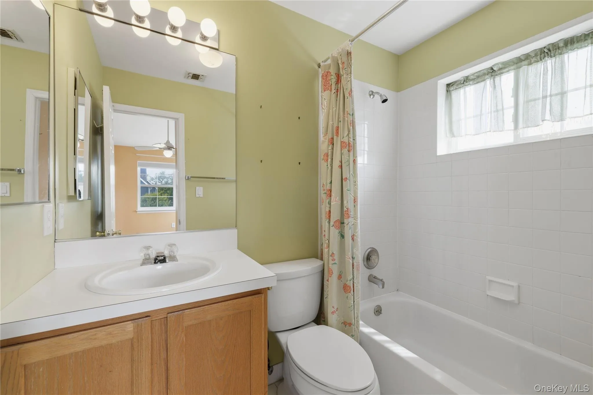 Second ensuite bathroom featuring a white ceramic bathtub, white subway tile surround, and an upper transom window Second ensuite bathroom featuring a white ceramic bathtub, white subway tile surround, and an upper transom window