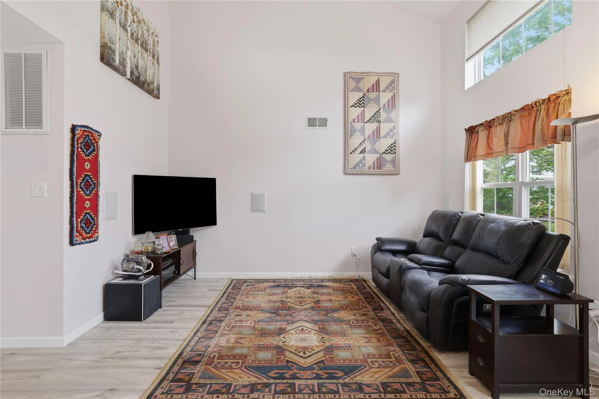 Spacious living area featuring light wood-finish flooring and vaulted ceilings Spacious living area featuring light wood-finish flooring and vaulted ceilings