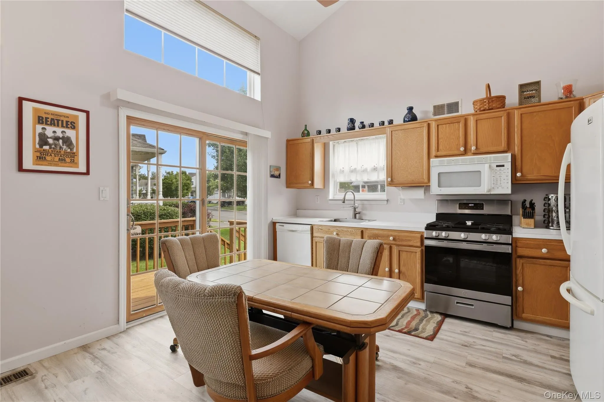 Kitchen featuring wood-finish flooring, light wood cabinetry, new stainless steel range, built-in microwave, and a glass sliding door leading to an outdoor deck Kitchen featuring wood-finish flooring, light wood cabinetry, new stainless steel range, built-in microwave, and a glass sliding door leading to an outdoor deck