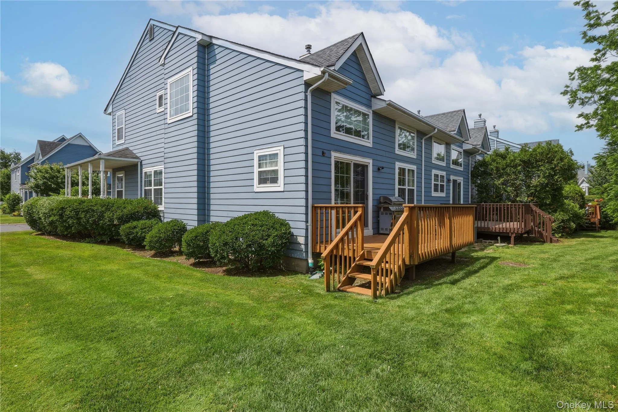 Rear deck and side of of unit showing expansive green lawn with established shrubbery Rear deck and side of of unit showing expansive green lawn with established shrubbery