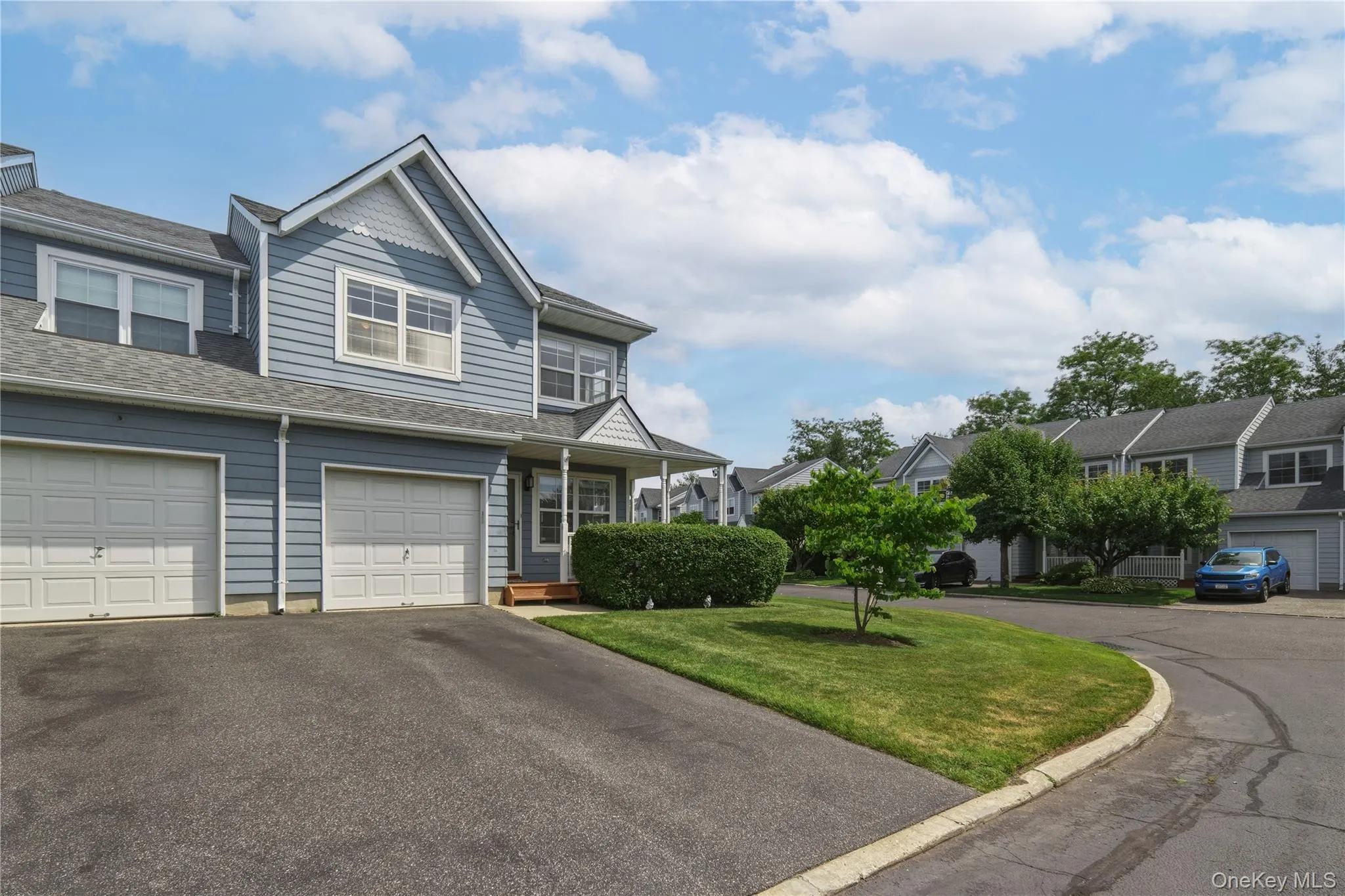 Blue siding exterior with white trim, featuring single-car garage, driveway, and a covered front wrap-around porch Blue siding exterior with white trim, featuring single-car garage, driveway, and a covered front wrap-around porch