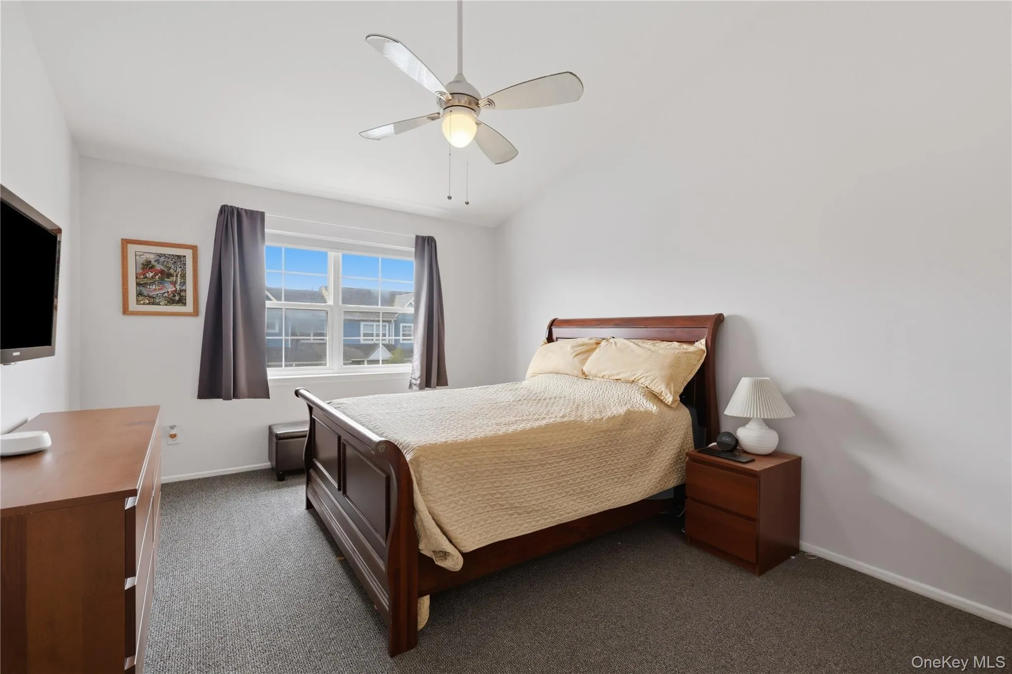 Bright bedroom featuring neutral wall tones and a ceiling fan with integrated lighting Bright bedroom featuring neutral wall tones and a ceiling fan with integrated lighting