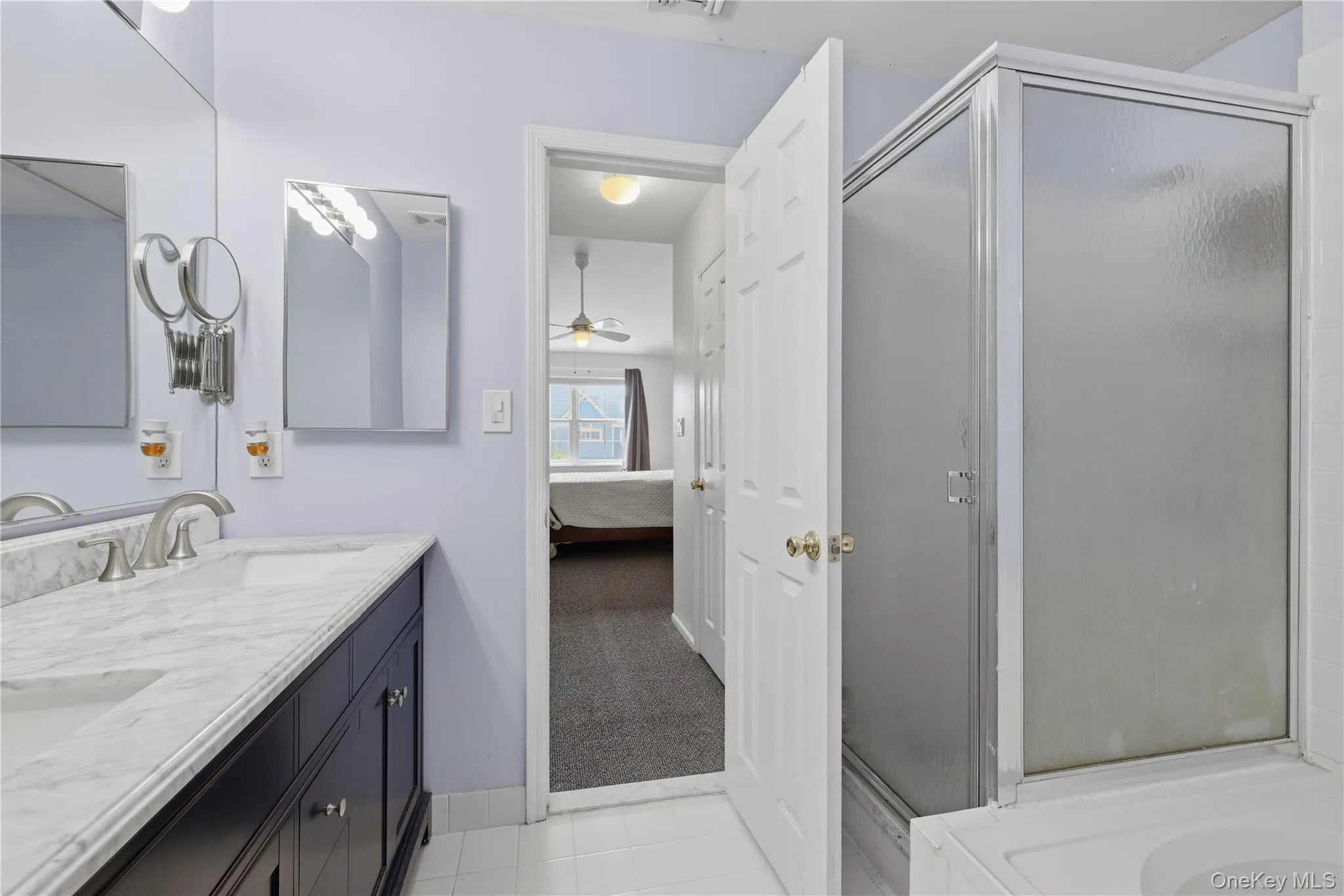 Primary ensuite bathroom featuring a double vanity with stone countertop, dual undermount sinks, and brushed nickel faucets Primary ensuite bathroom featuring a double vanity with stone countertop, dual undermount sinks, and brushed nickel faucets