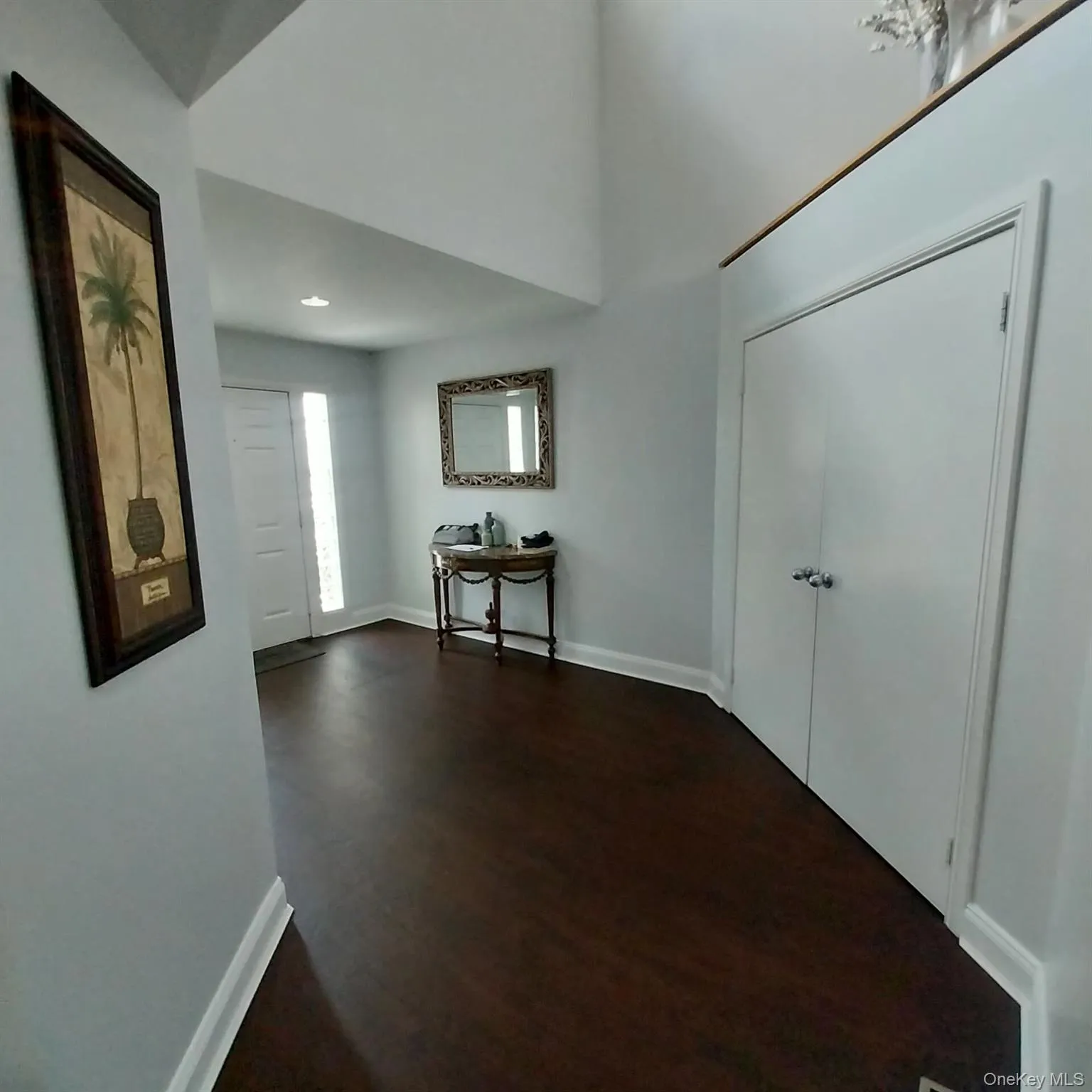 Entryway featuring dark wood-finish flooring, white baseboards, and light gray walls Entryway featuring dark wood-finish flooring, white baseboards, and light gray walls